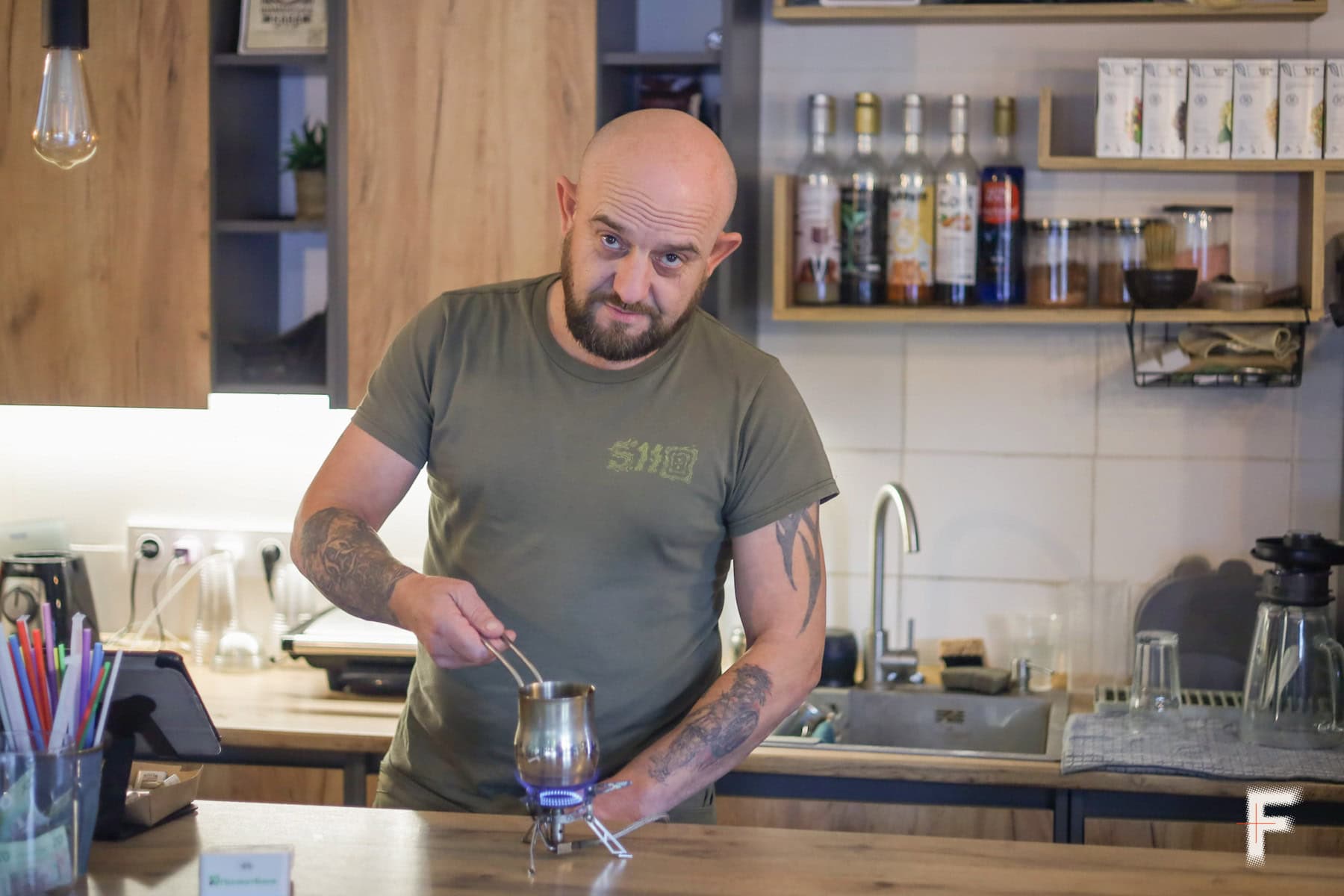 Чоловік дивиться в камеру та готує каву на кухні