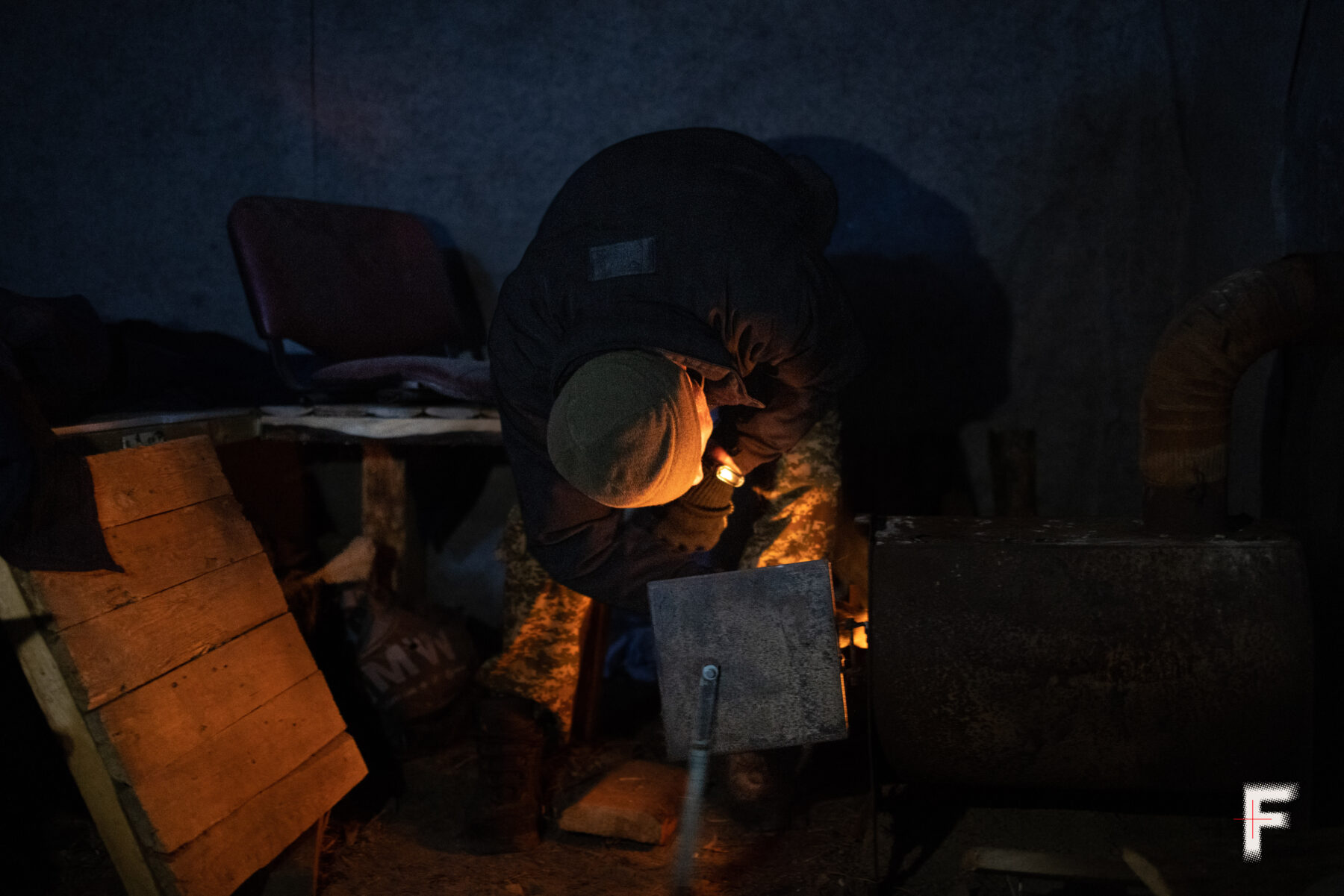 Війсковий розпалює буржуйку щоб зігріти бійців мобільної вогневої групи.