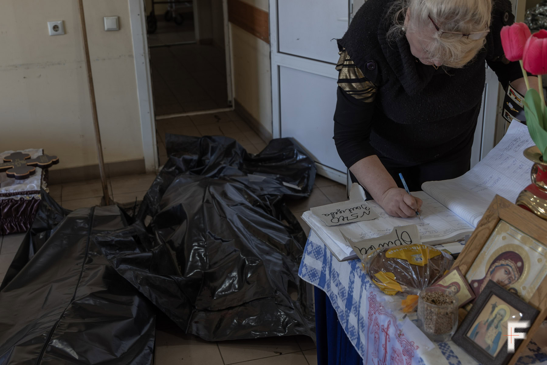 Жінка заповнює журнал реєстрації видачі тіл, морг Слов'янська