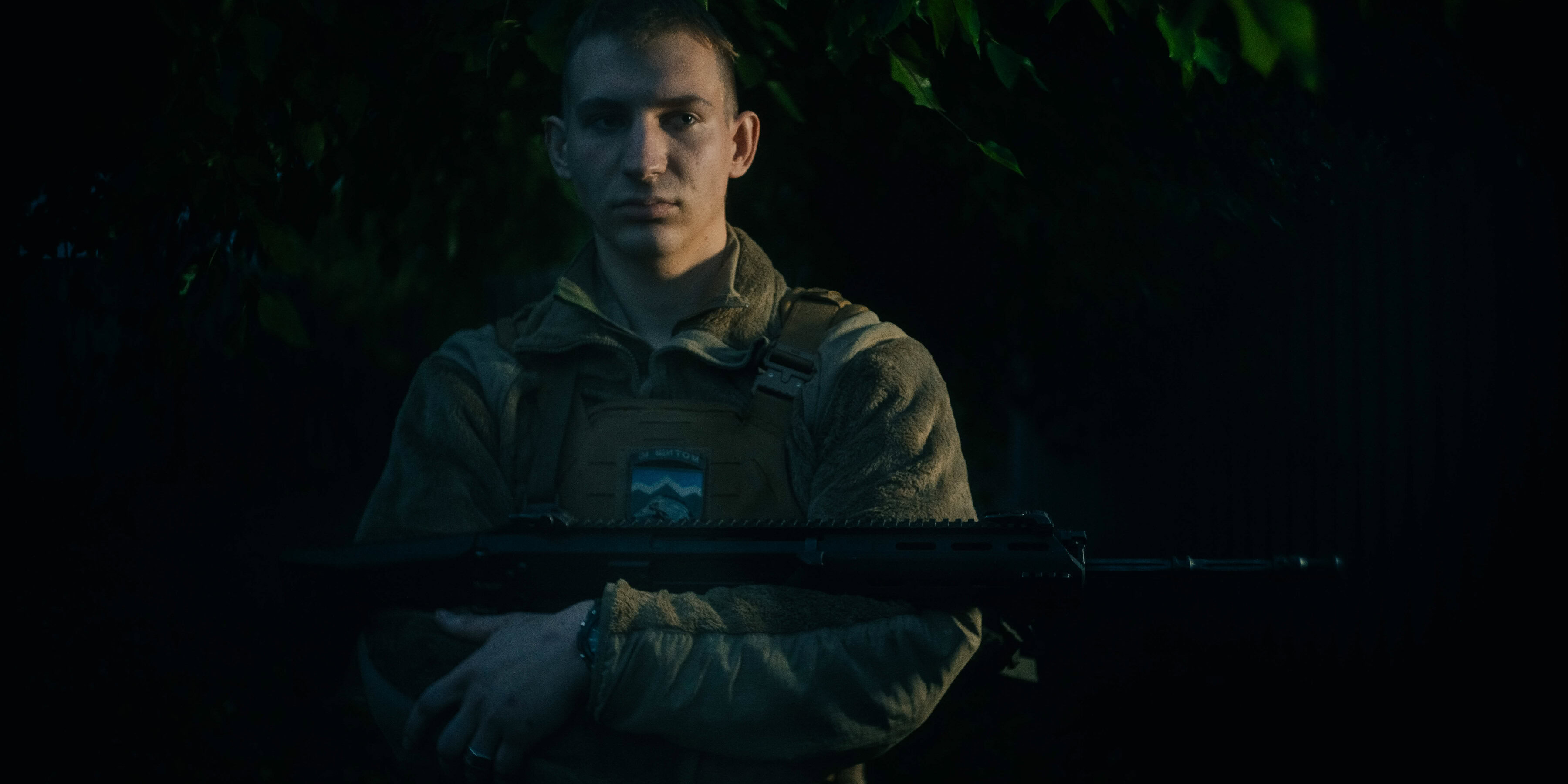 Військовий стоїть в темряві та тримає амуніцію