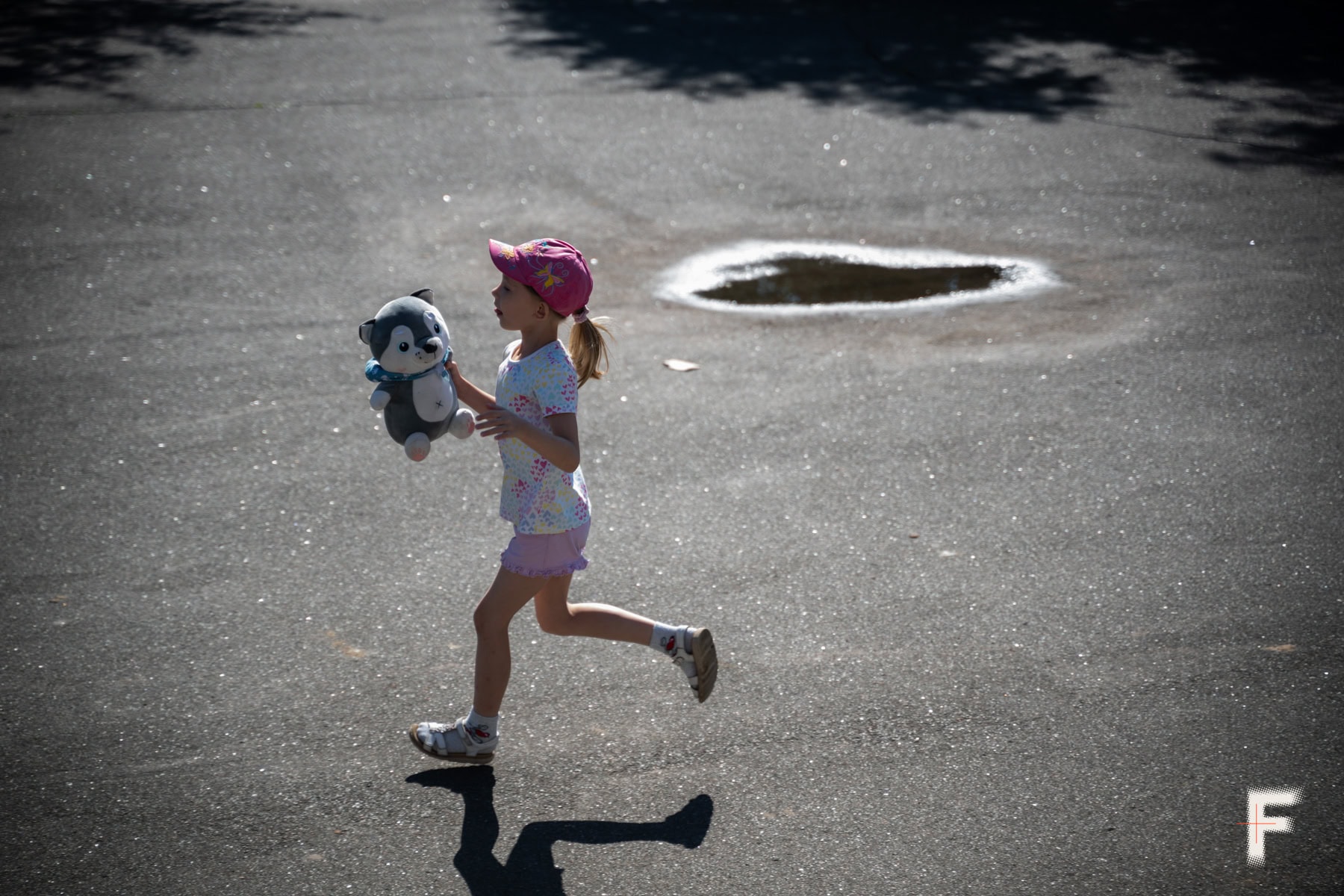 Маленька дівчинка біжить із іграшкою на вулиці.