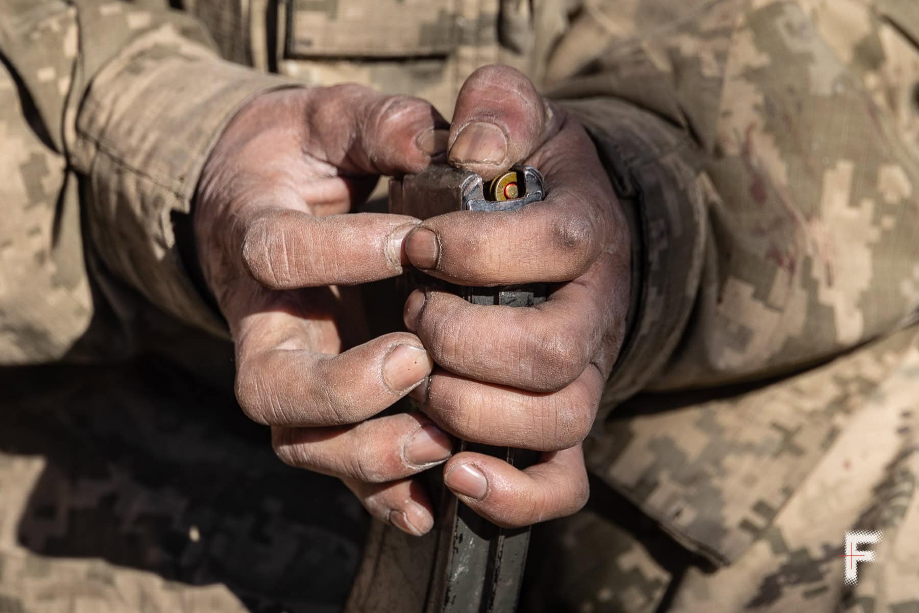 Руки захисника заряджають зброю.