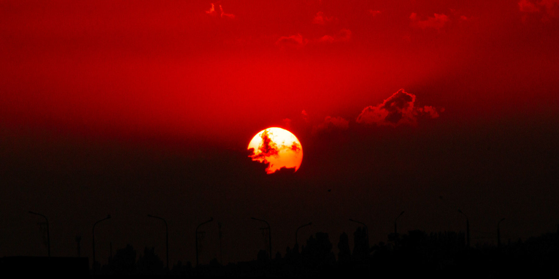 Захід сонця над Україною — червоні та чорні відтінки неба створюють драматичний пейзаж.