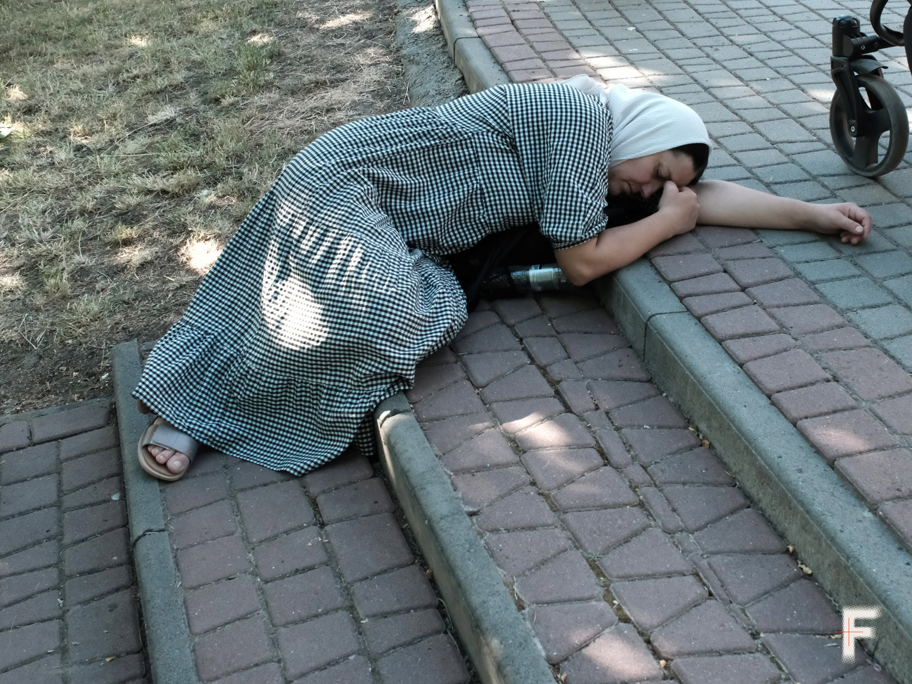 Жінка сидить на тротуарі під час хресної ходи в Чернівецькій області