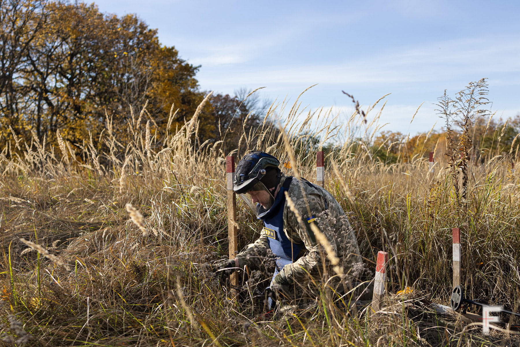 Сапер із детектором шукає міни в полі