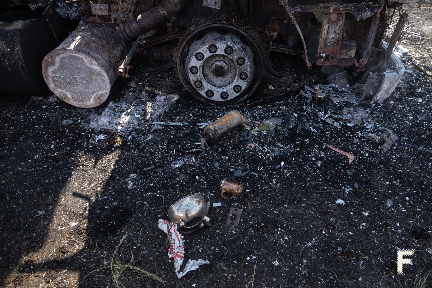 Чайник і чашка стоять біля вигорілої вщент автівки після російського удару.