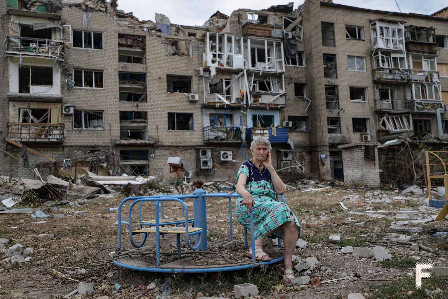 Літня жінка сидить навпроти зруйноваго будинку Покровьк