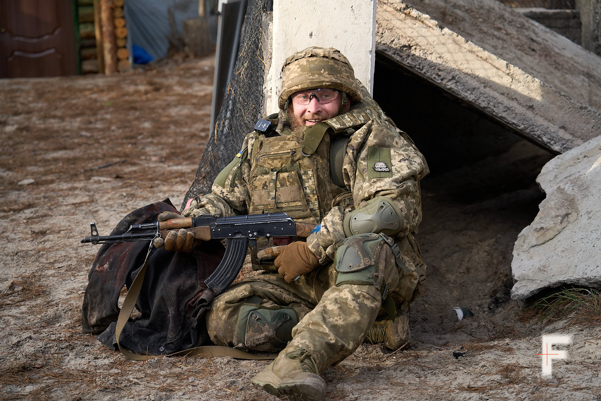 Курсант сидить на підлозі у військовій формі та тримає навчальну зброю