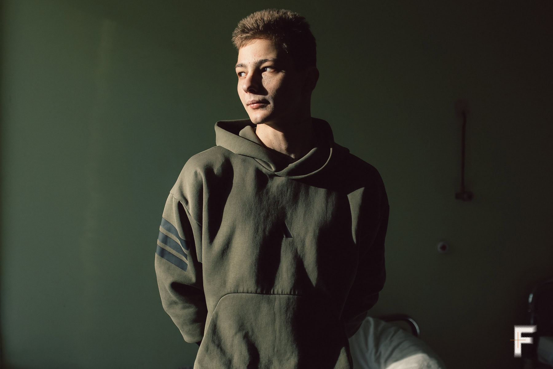 Молодий чоловік у світшоті дивиться ліворуч, обличчя освітлене природним світлом