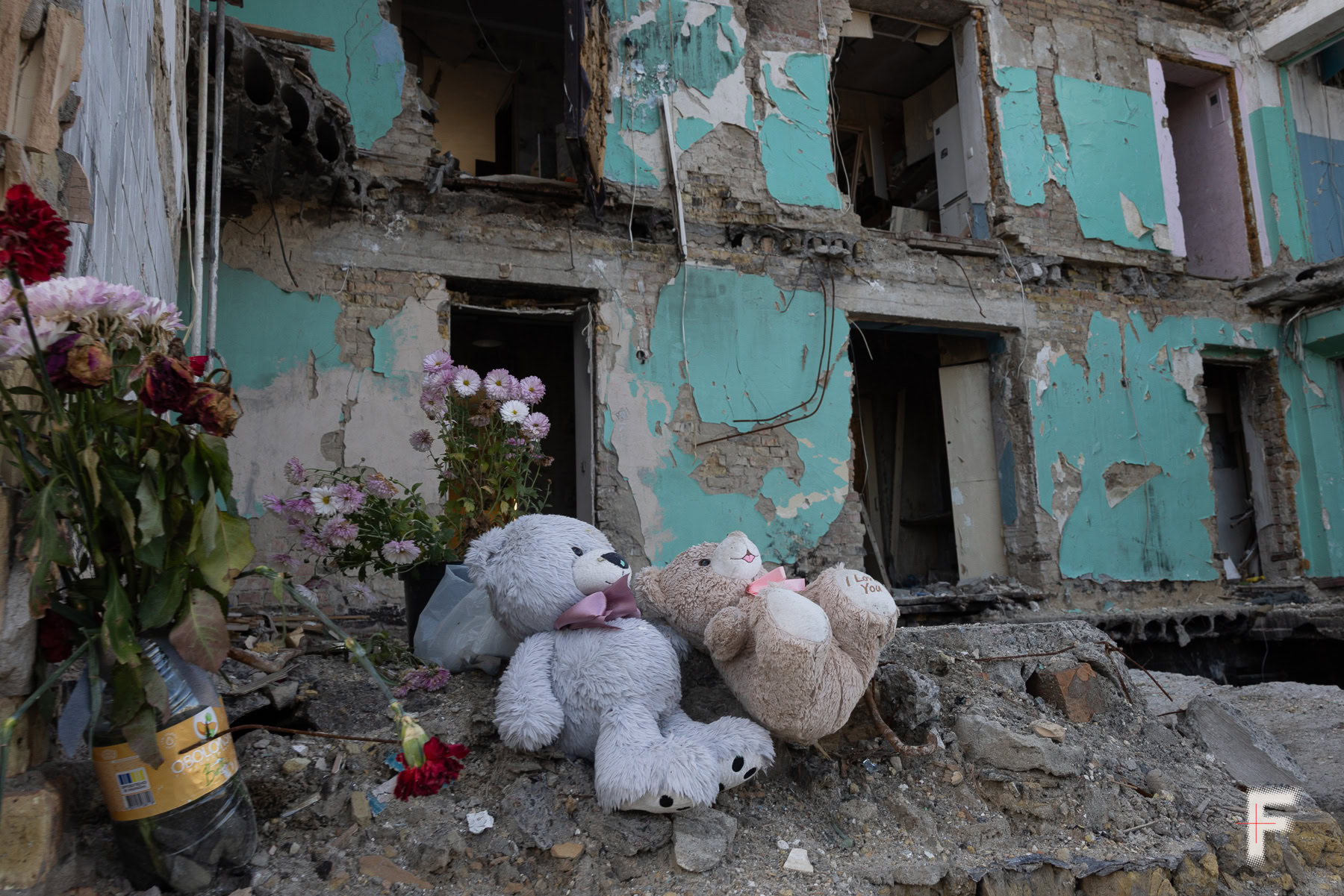 Квіти та м’які іграшки, залишені як меморіал біля зруйнованого будинку.