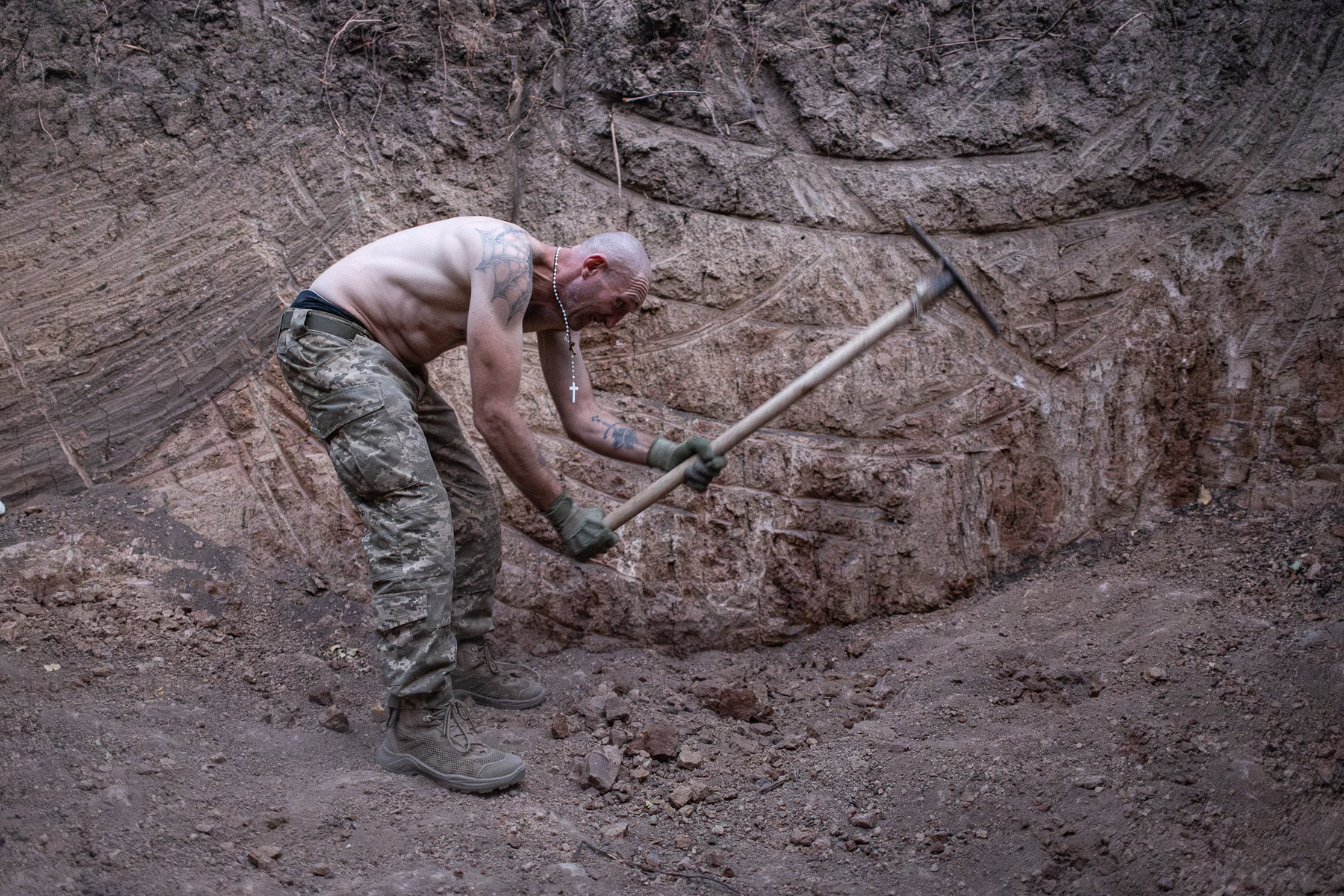 Боєць «Локомотив» з-поміж колишніх ув’язнених копає яму киркою для бліндажу в польовому таборі 1 ОШП, 19 серпня 2024 року.