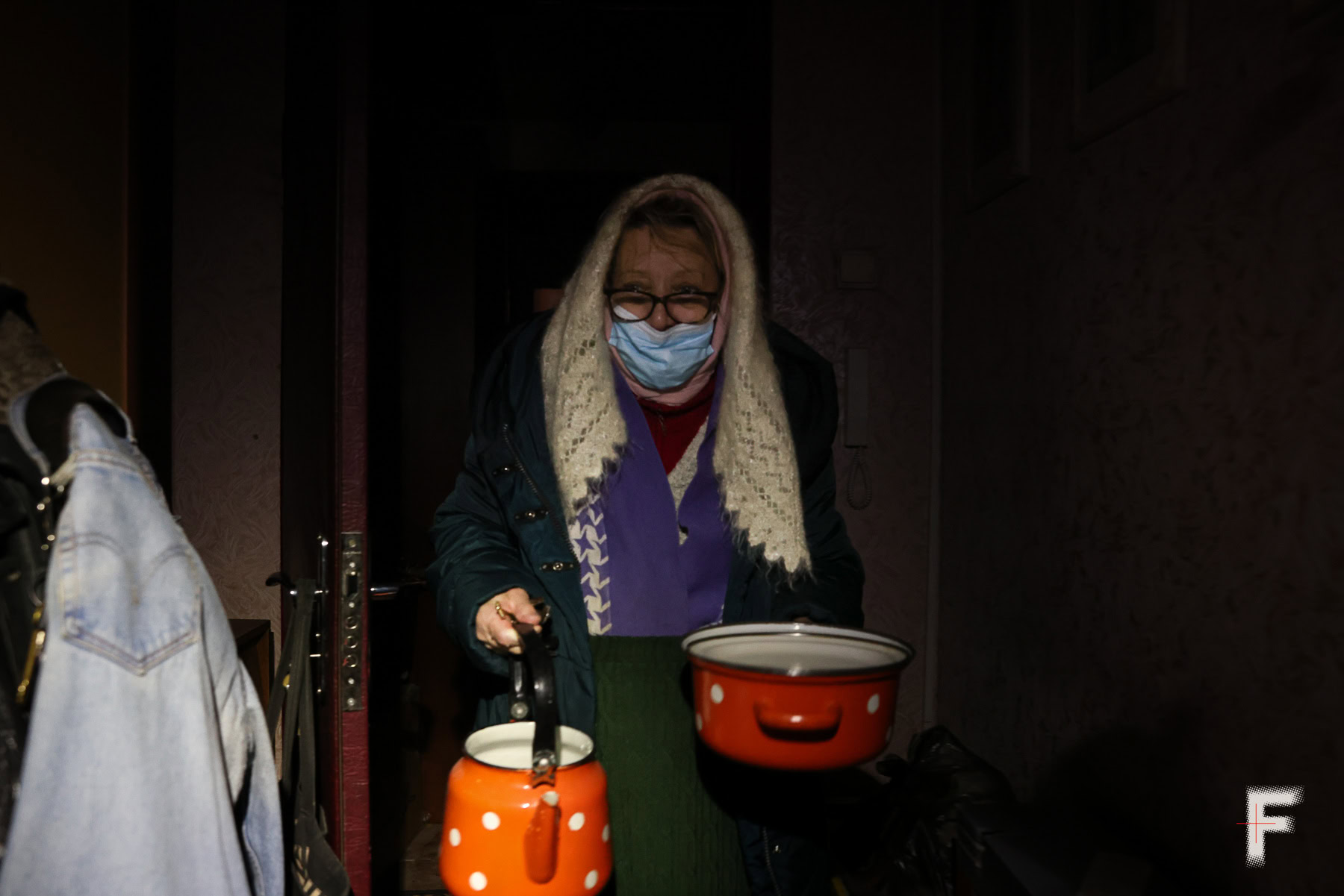 Сусідка Марія Станіславівна несе чайник і каструлю, щоб перелити воду у квартирі під час блекауту.