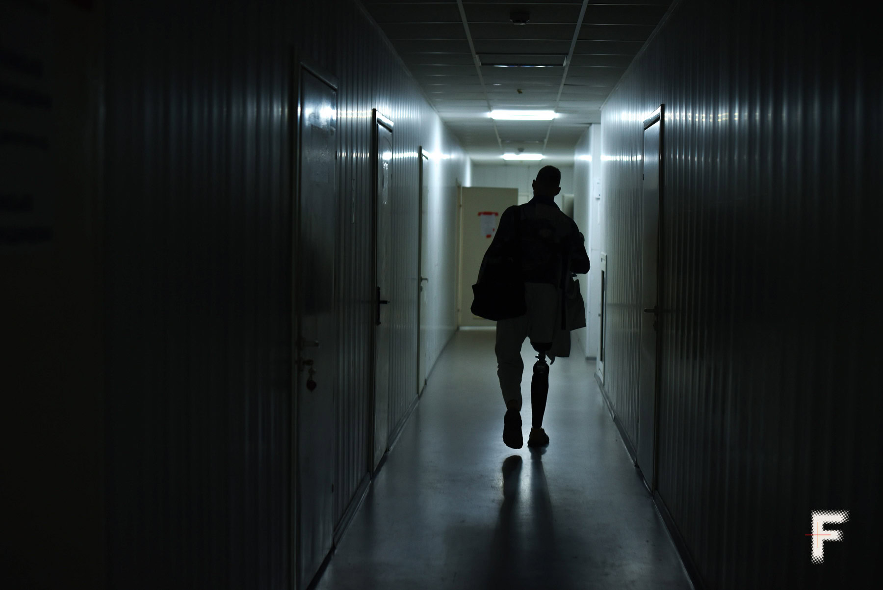 Ветеран з протезою ноги йде темним коридором, символ відновлення після війни.