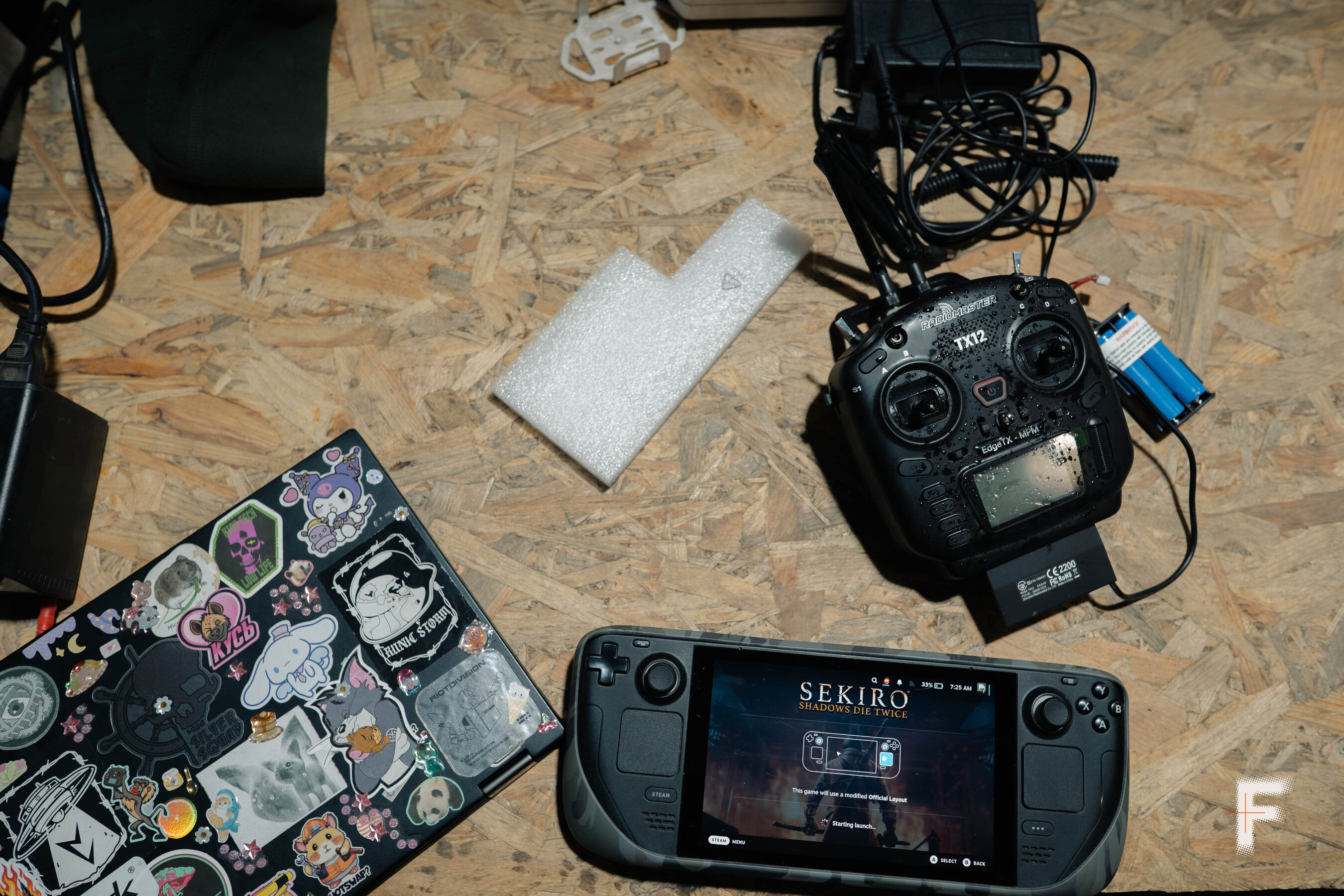 Пульт керування військовим дроном і ноутбук лежать на підлозі з пресованого дерева в робочому просторі.