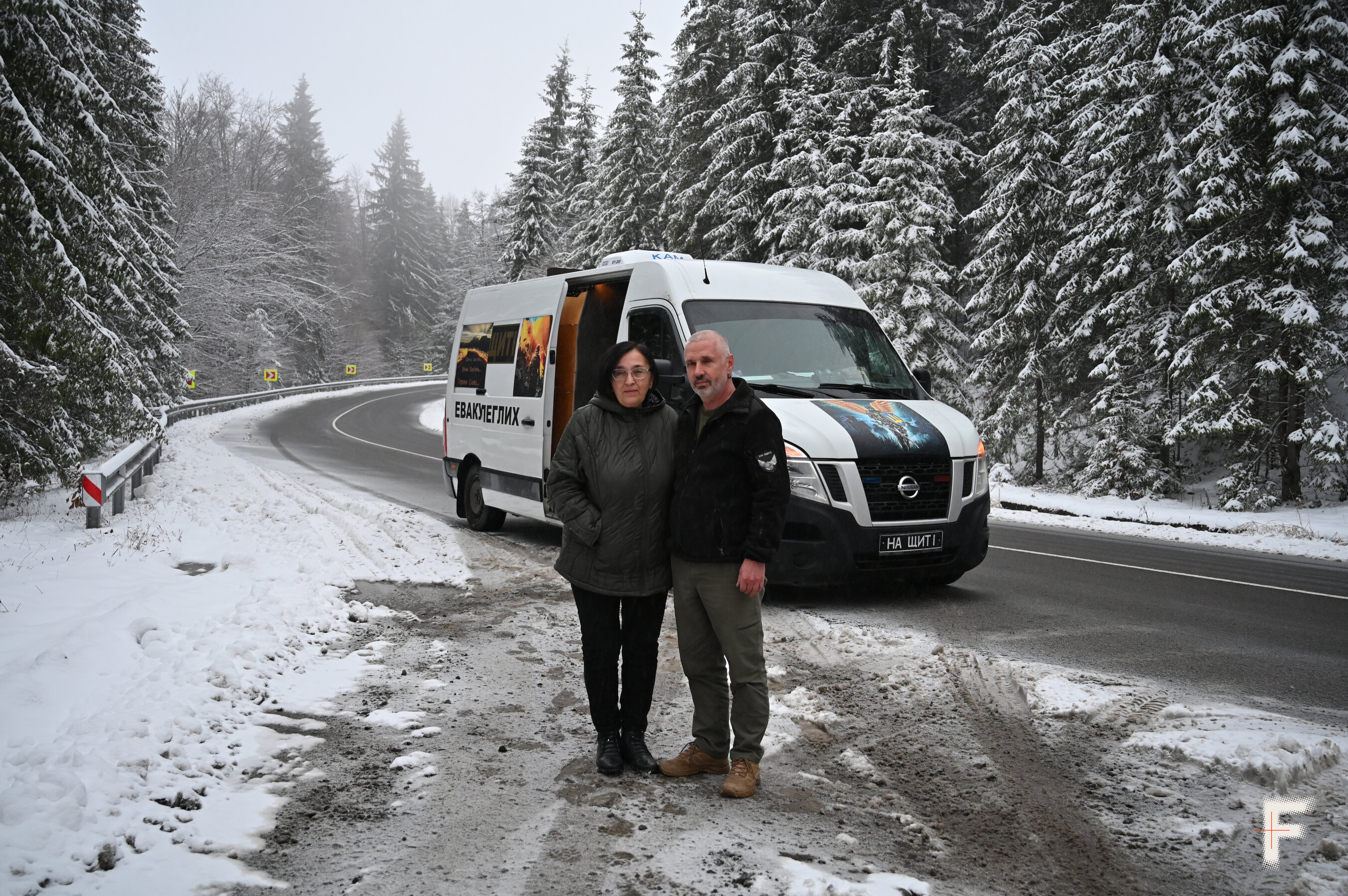 Чоловік і жінка стоять біля мінібуса серед снігу