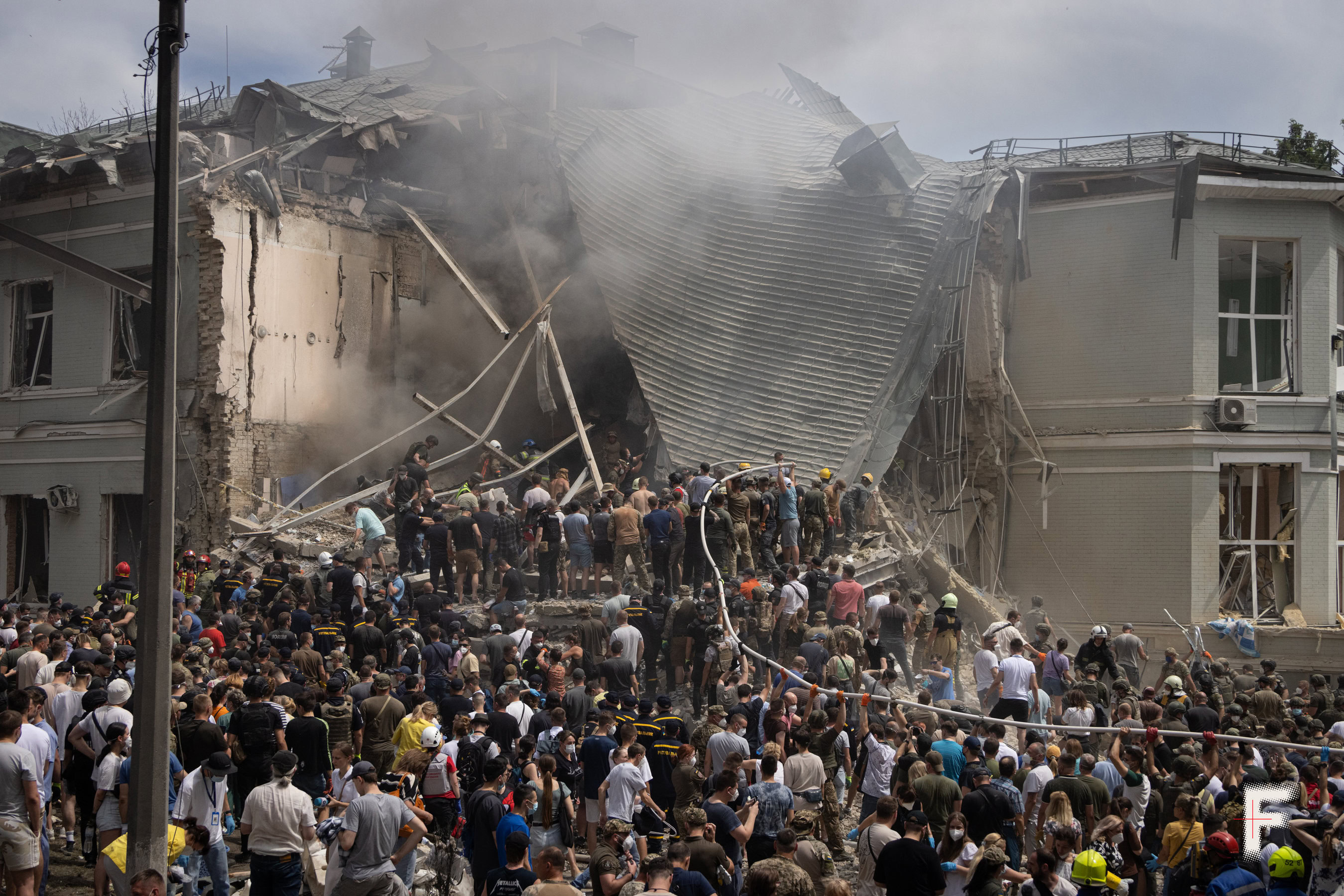 Люди розбирають завали зруйнованої лікарні після авіаудару, спільно очищаючи територію від уламків.