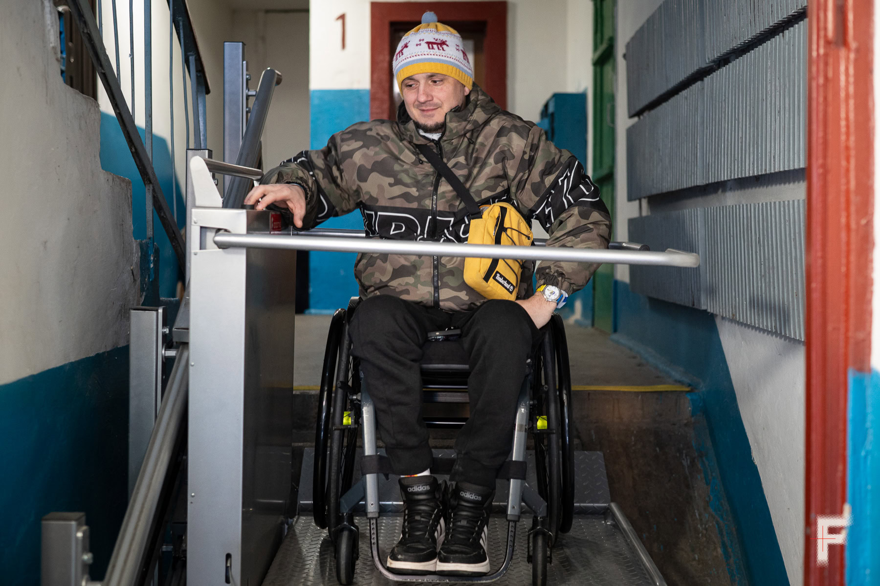 Ветеран спускається спеціальним підйомником у під’їзді.