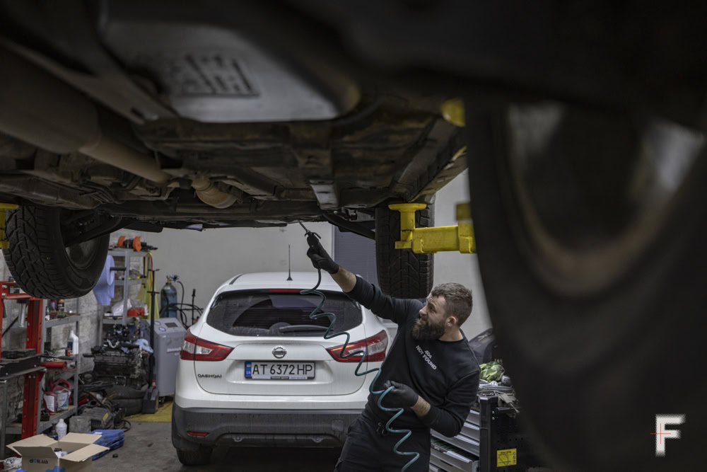 Чоловік проводить технічне обслуговування автомобіля, виконуючи заміну масла.