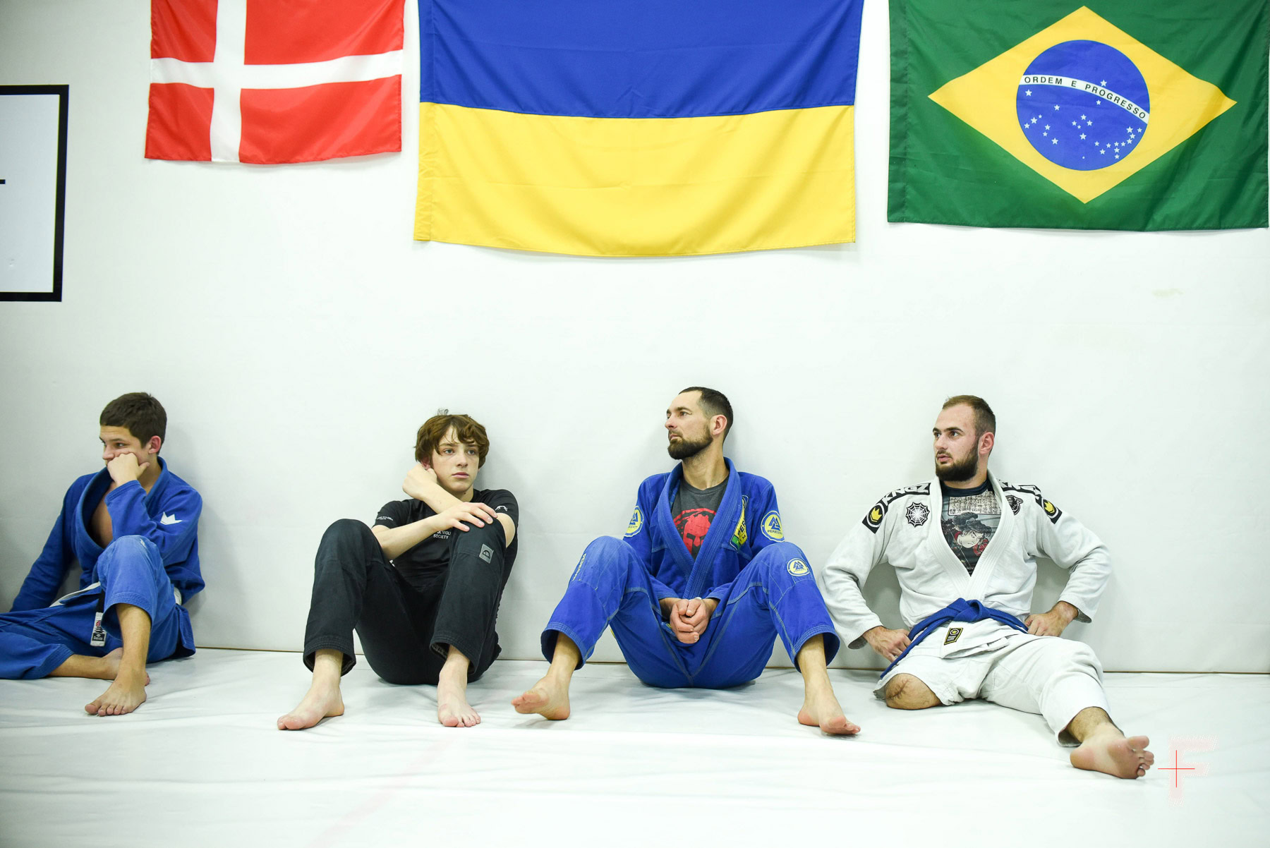 Учасники тренування з джиу-джитсу сидять на татамі, готуючись до поєдинків.