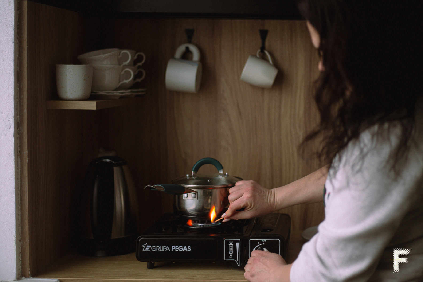 Руки жінки запалюють портативну газову плиту в умовах відсутності електрики.