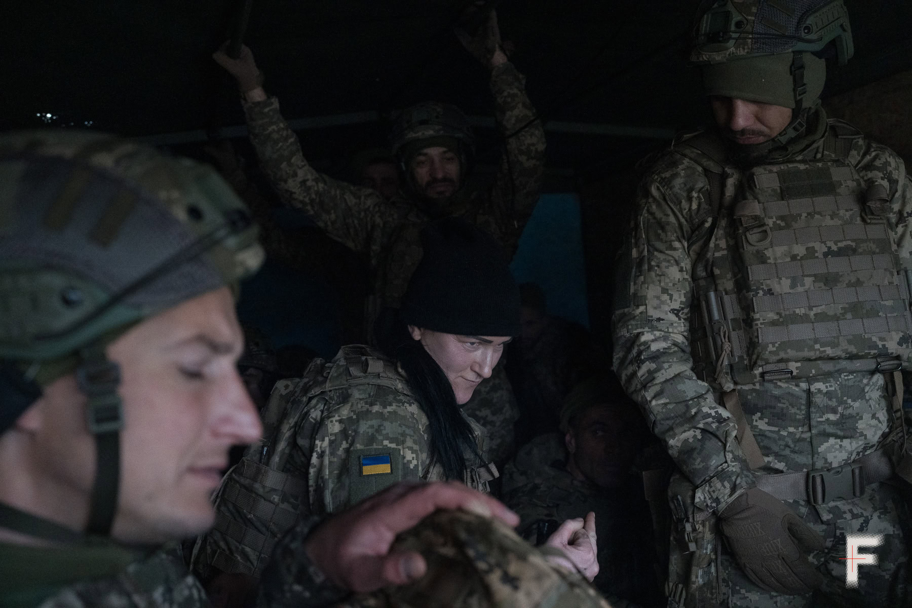 Жінка-військова стоїть серед чоловіків-військовослужбовців.