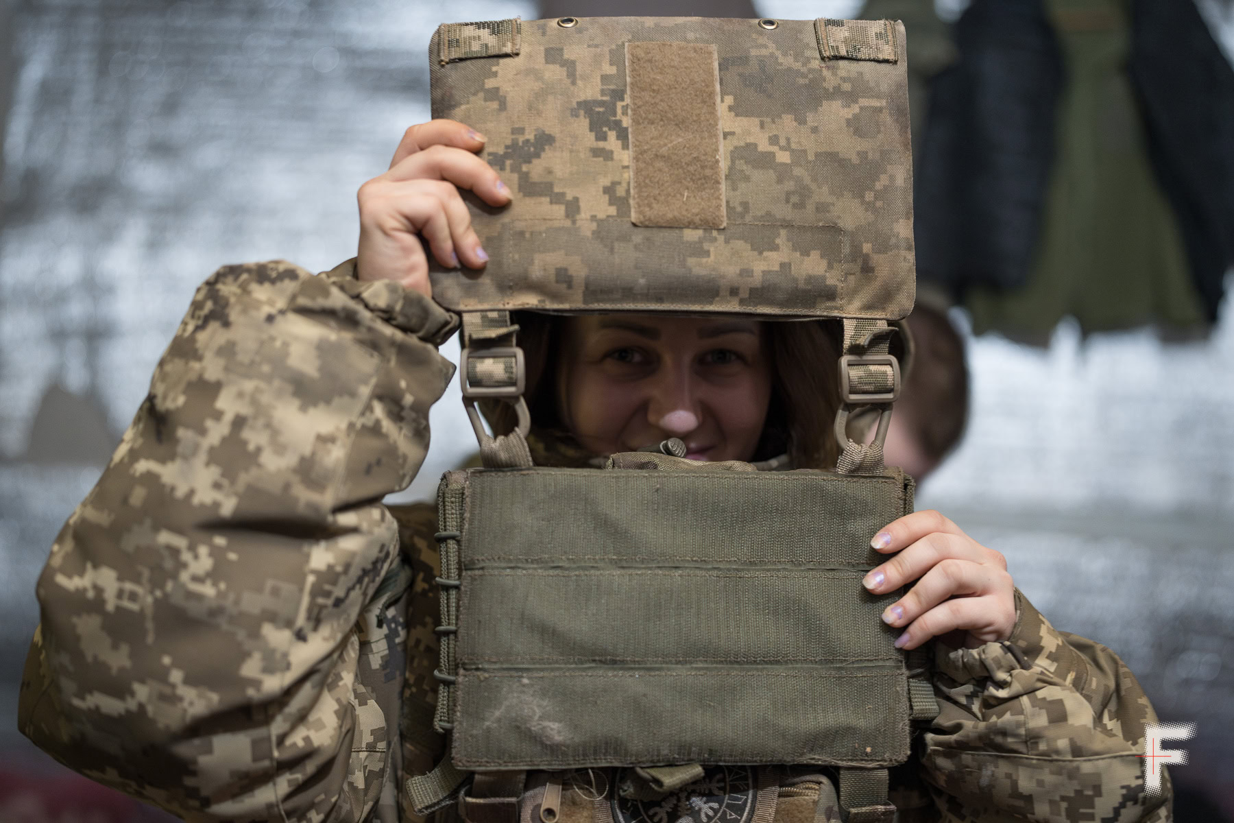 Колишня ув’язнена у військовій формі дивиться в об’єктив, тримаючи бронежилет.