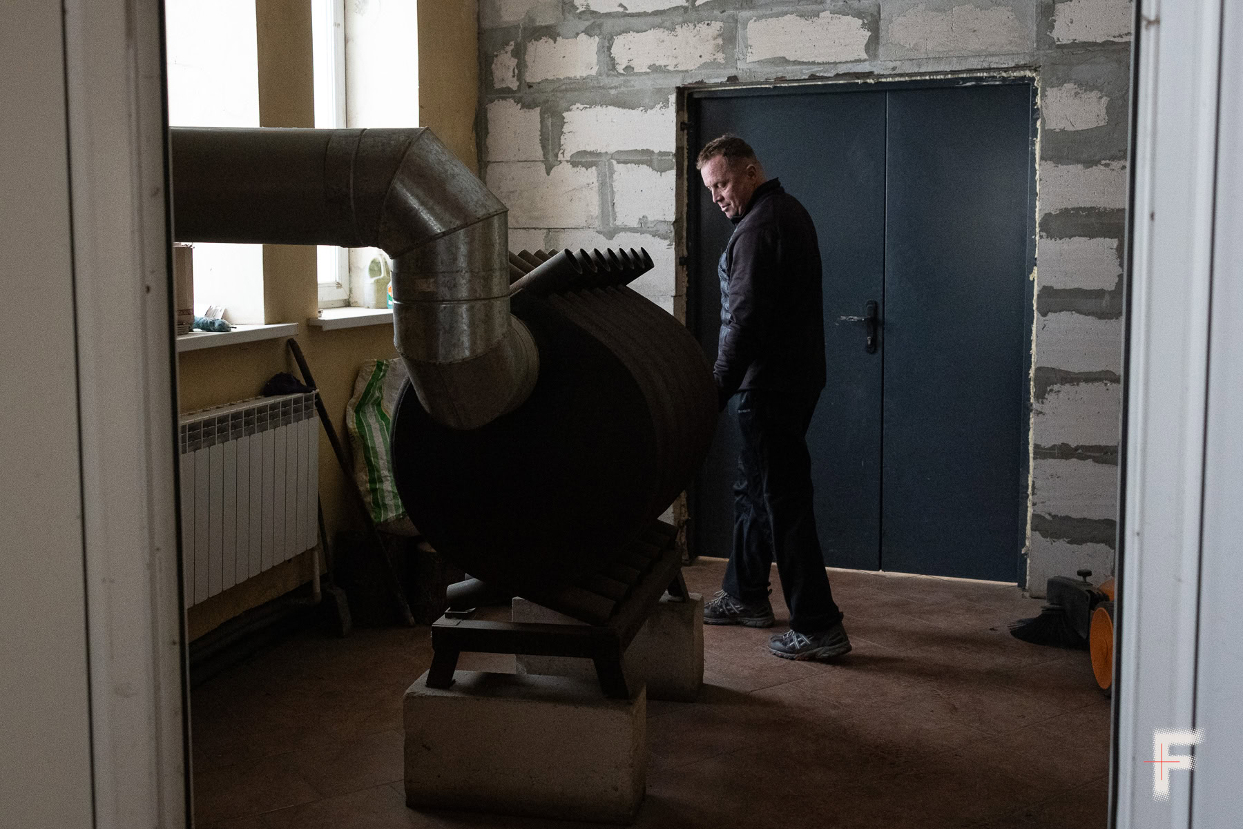 Працівник зоопарку закладає дрова у велику котельню для обігріву тварин узимку.