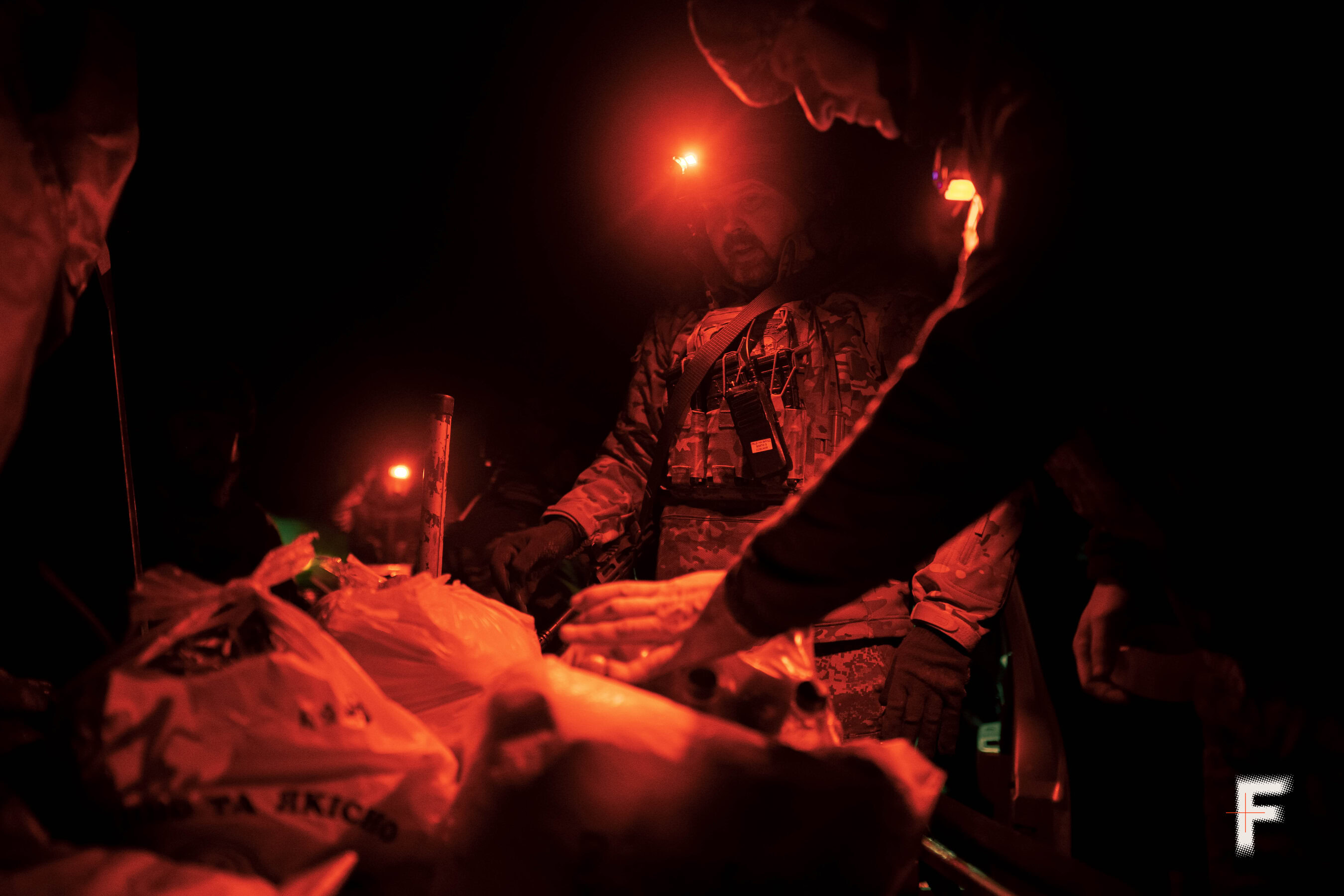 Військові перевіряють продовольче забезпечення, закріплене на наземному роботі.