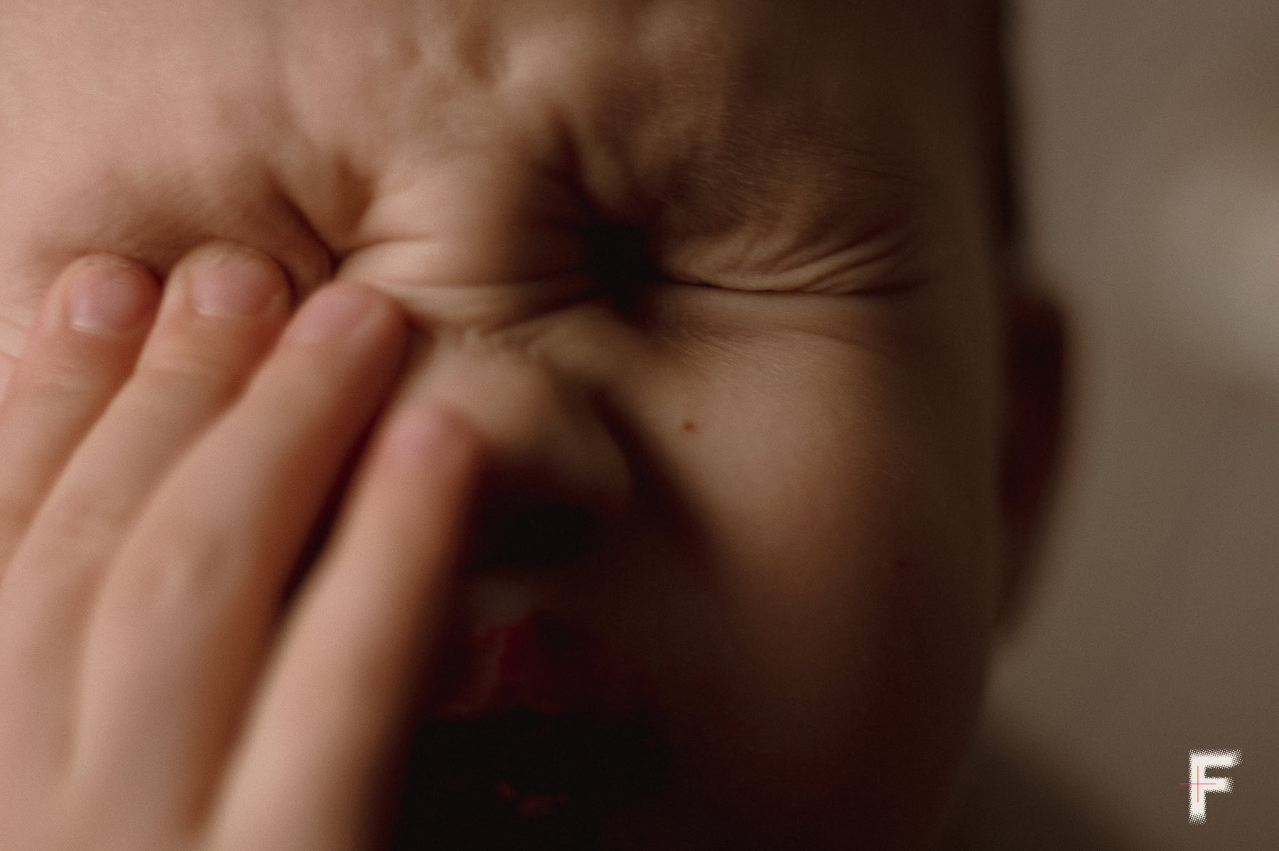 Маленька дитина торкається руками очей у квартирі.