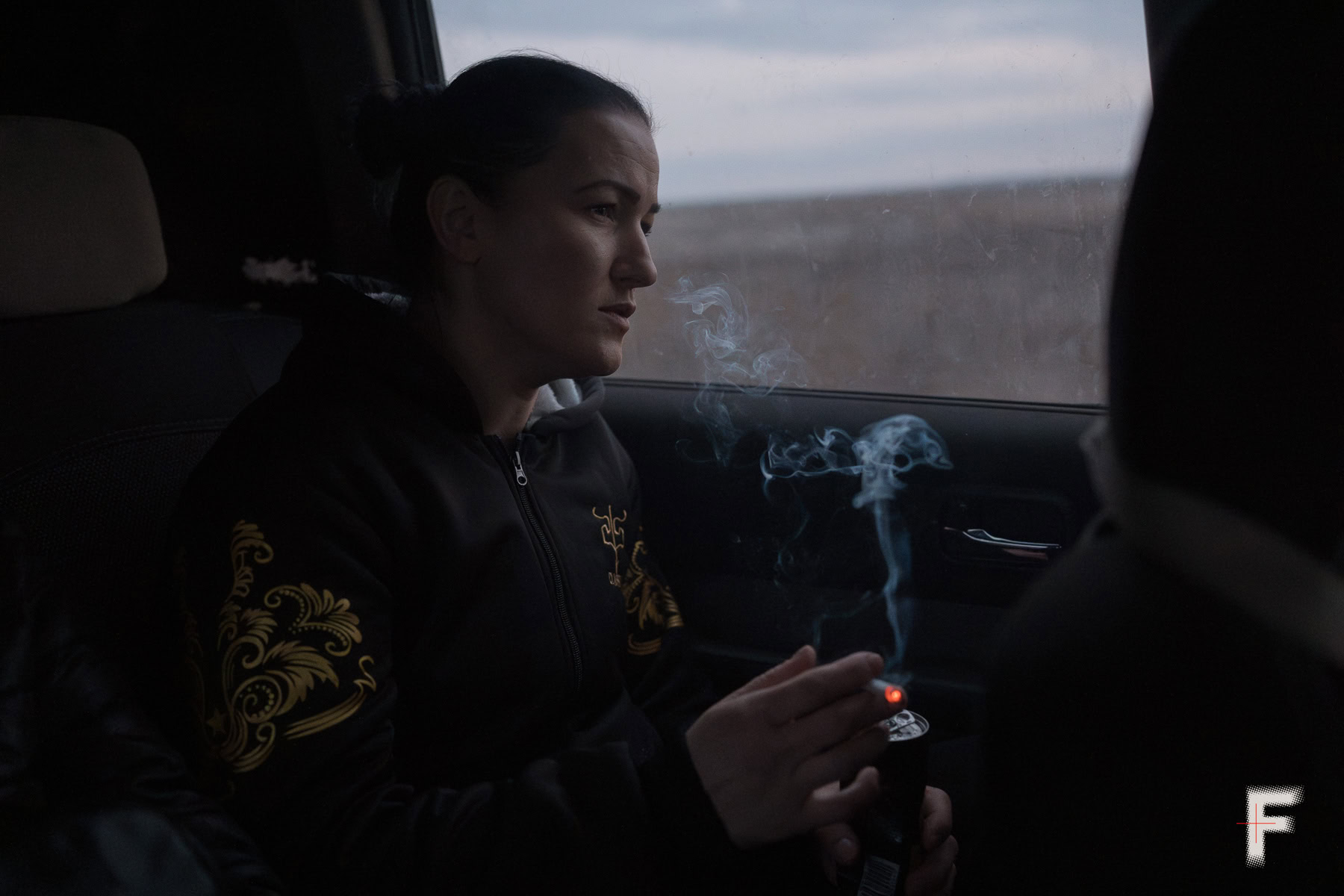 Колишня ув’язнена жінка курить в автомобілі у цивільному одязі.