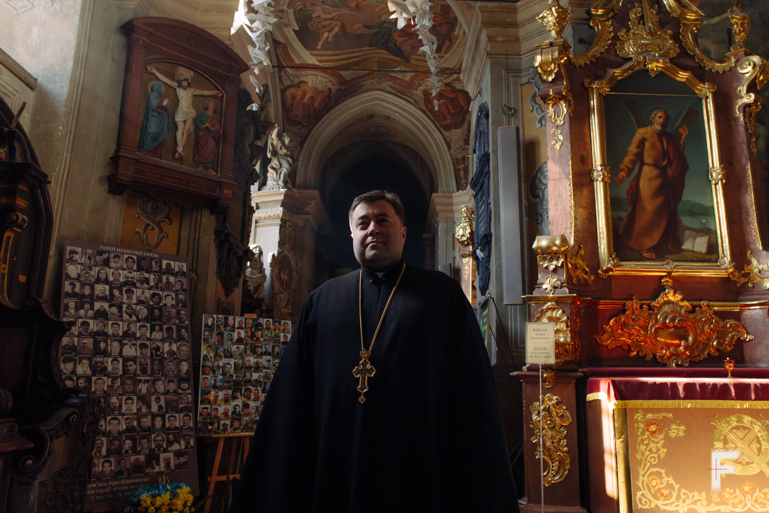 Портрет священника Тараса на фоні ікон та фотографій загиблих військових