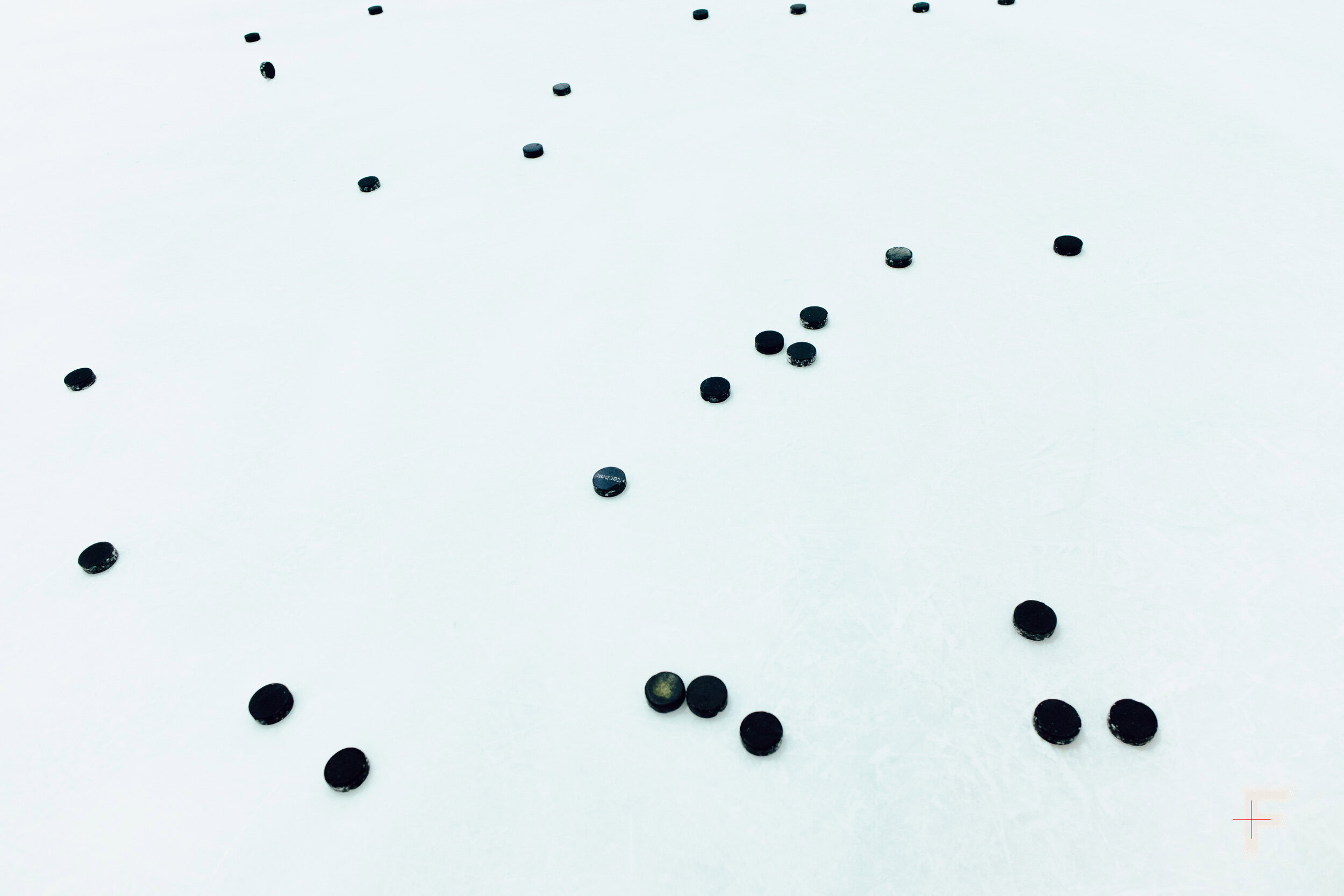 Хокейні шайби розкидані по льоду перед початком гри