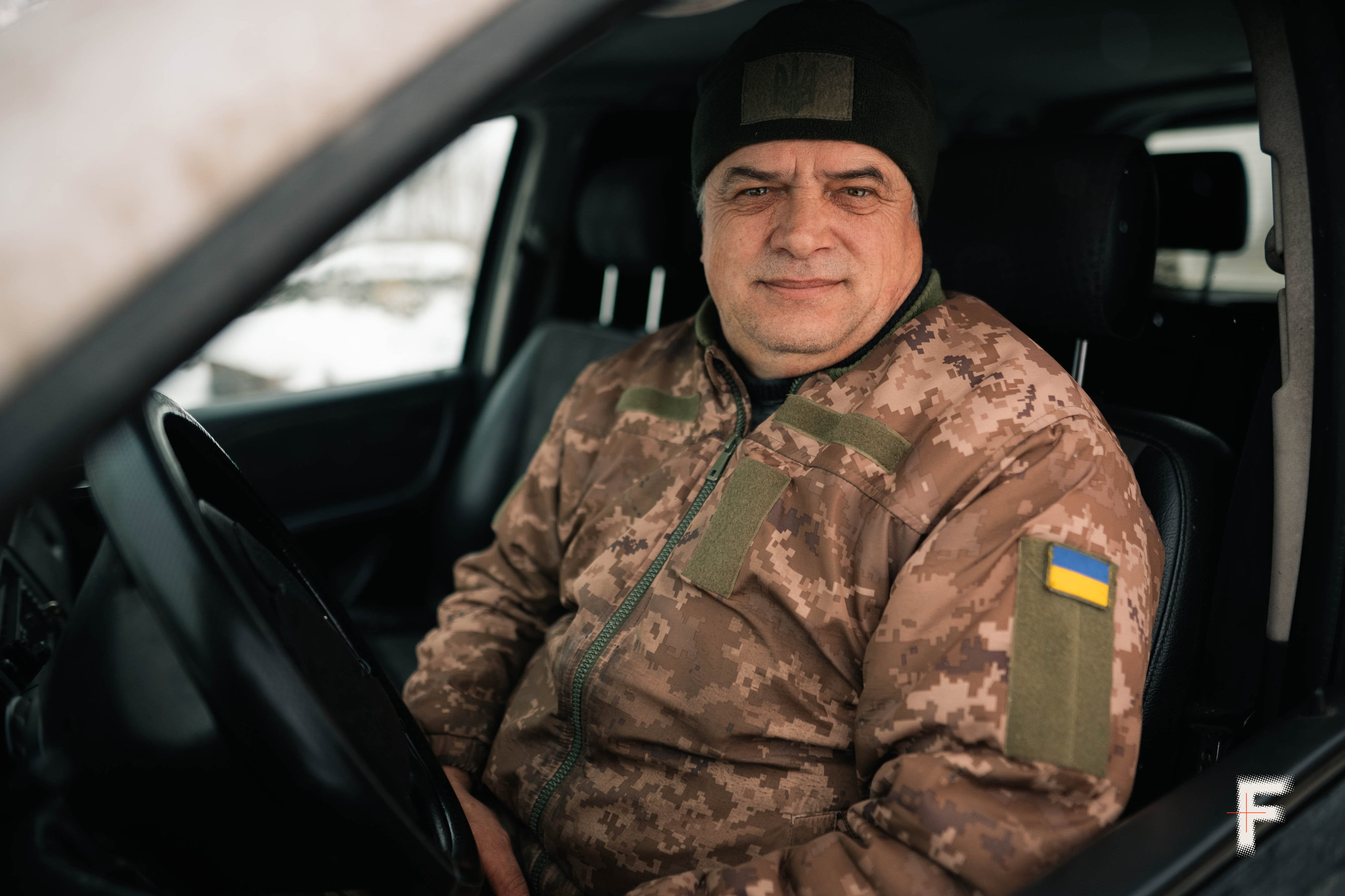 Літній чоловік у військовій формі України сидить за кермом автомобіля