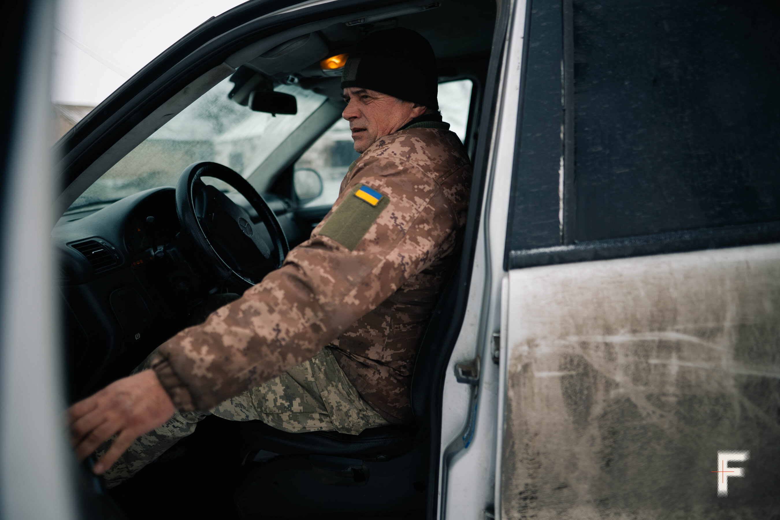 Літній чоловік у військовій формі зачиняє двері автомобіля