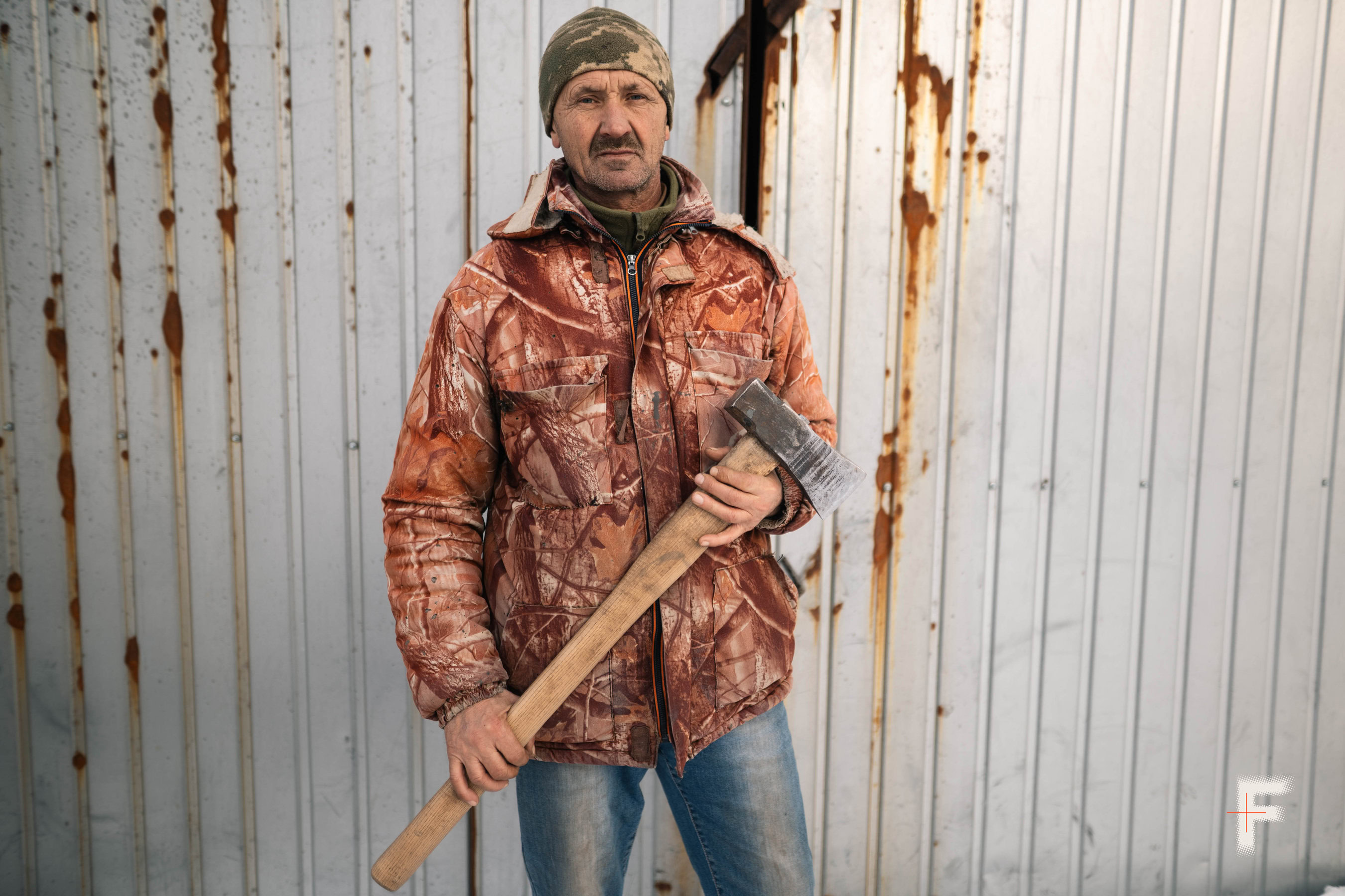 Літній чоловік тримає сокиру в руці на вулиці