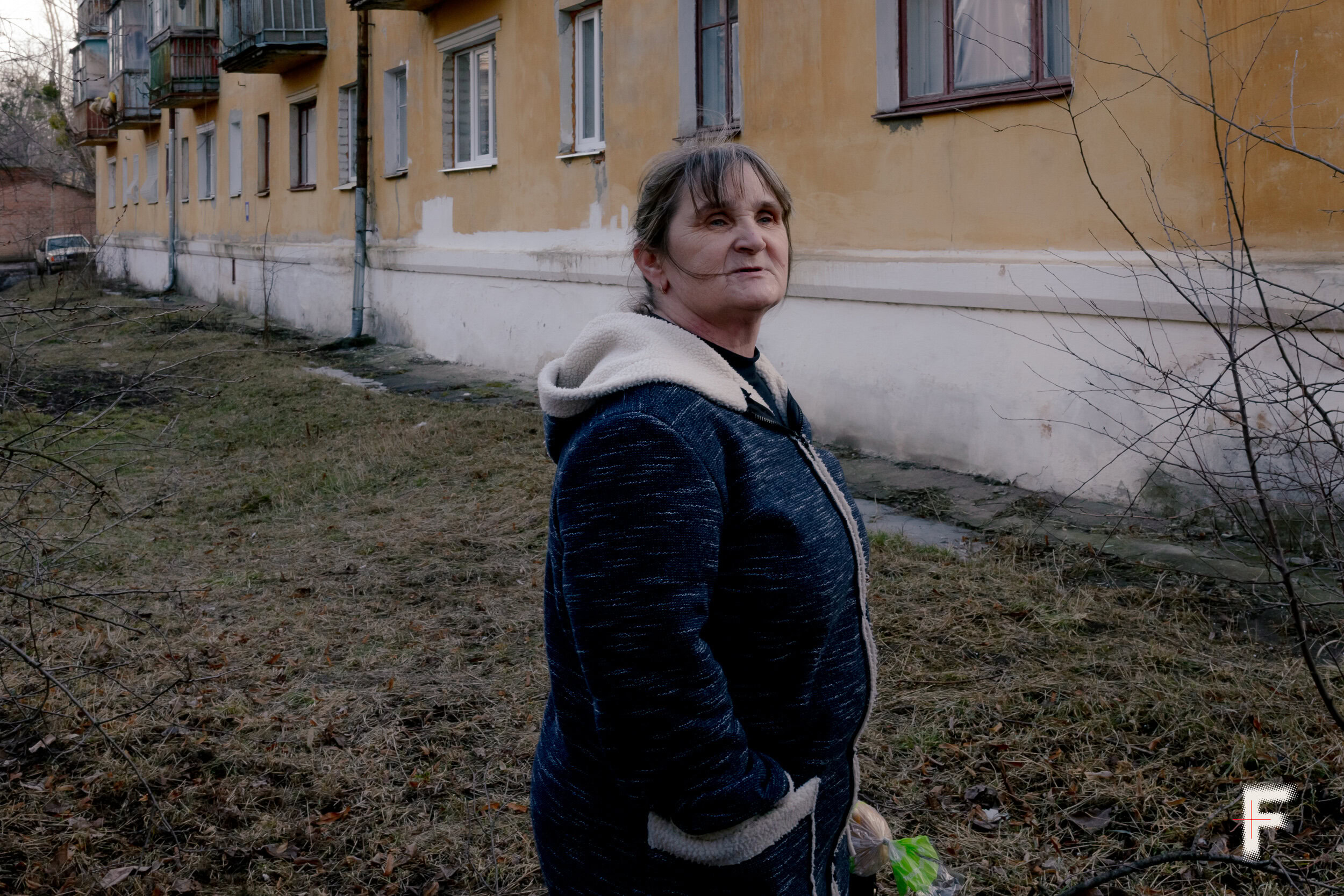 Жінка стоїть у дворі житлового будинку в Ізюмі