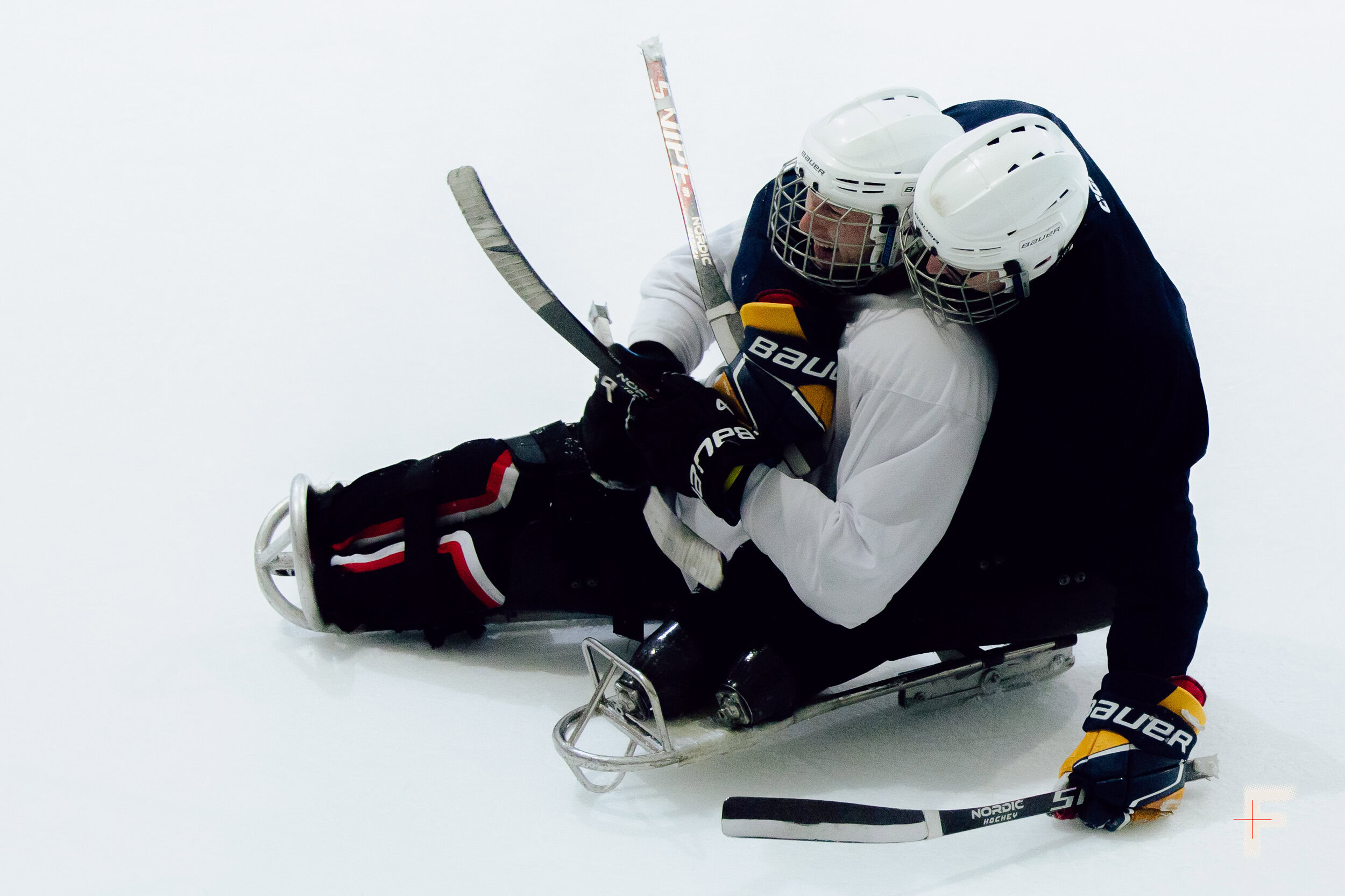 Двоє ветеранів з ампутаціями пересуваються по льоду під час гри в хокей