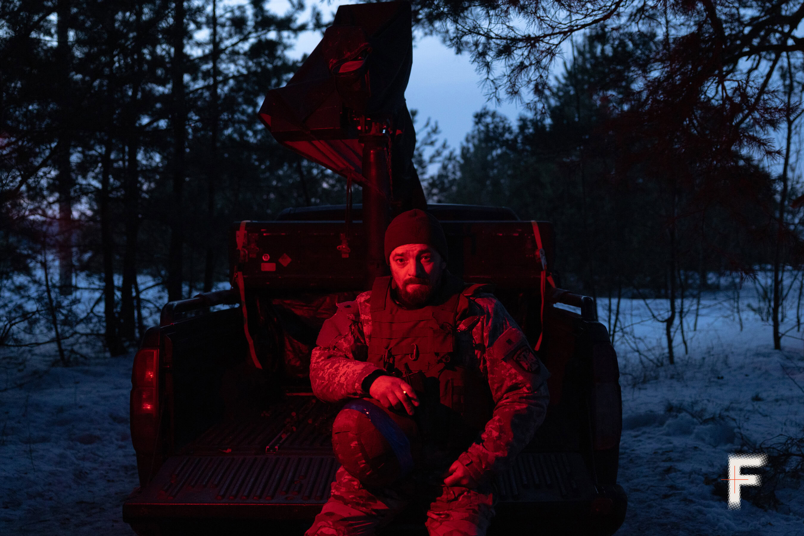 Командир мобільної вогневої групи сидить на кузові пікапа під час нічного чергування.