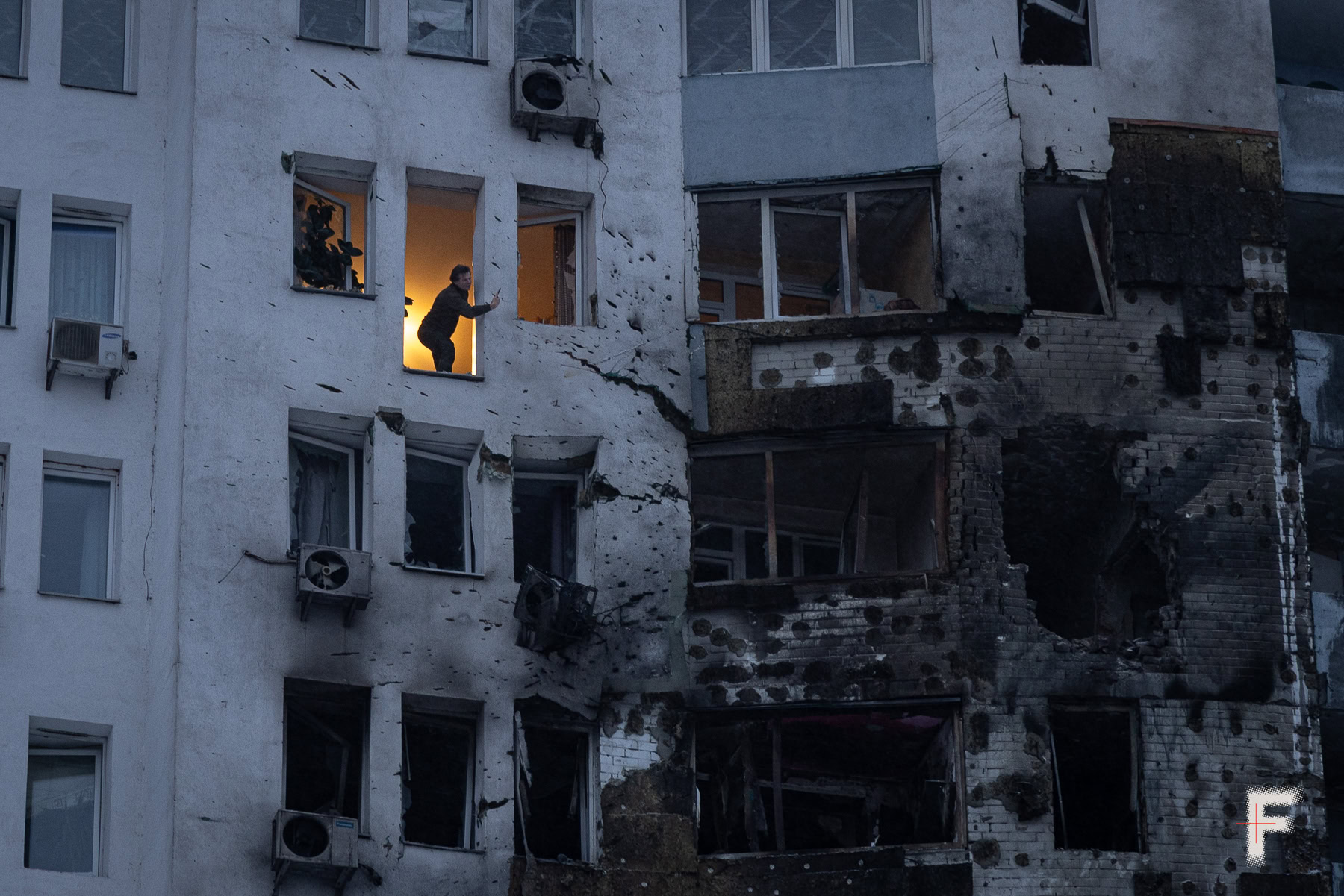 Чоловік знімає наслідки нічного влучення в житловий будинок під час атаки російських військ на Київ