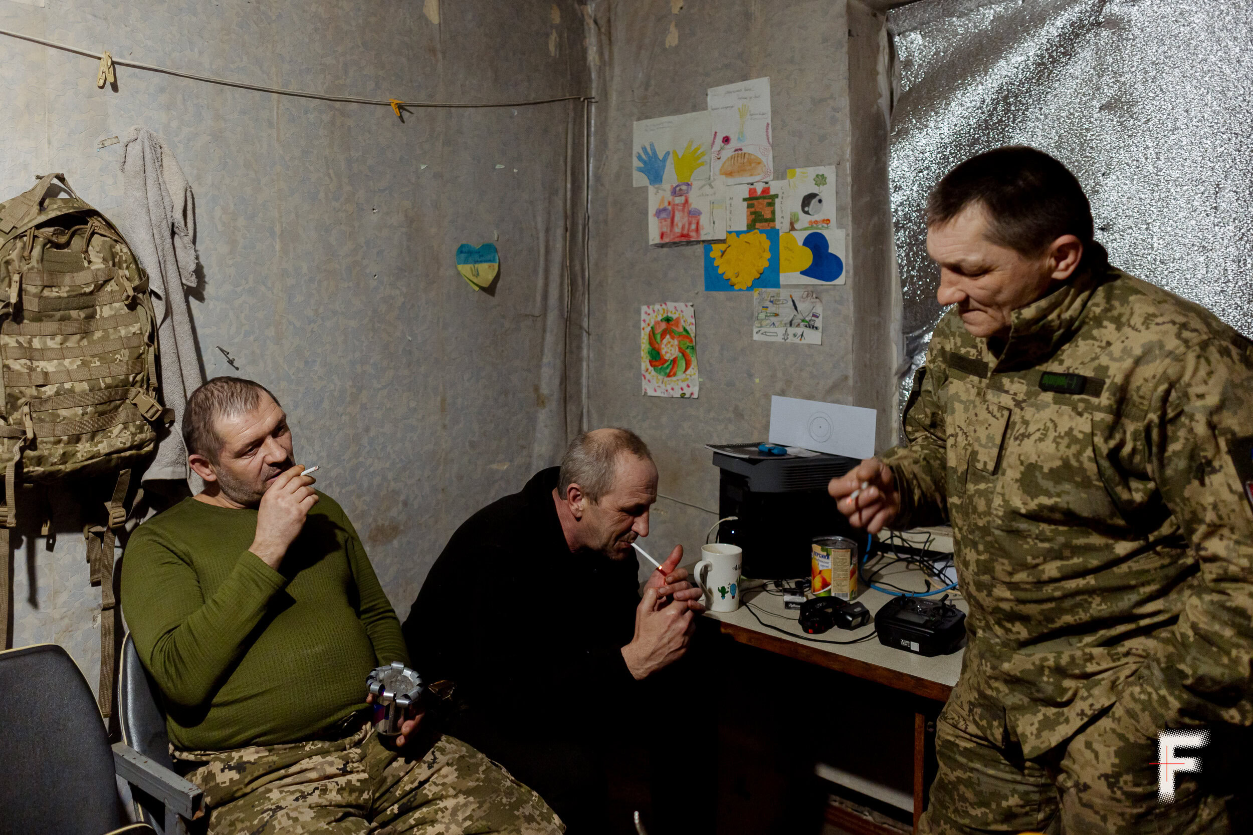 Українські військові в камуфляжі оглядають і ремонтують наземний роботизований пристрій (UGV)