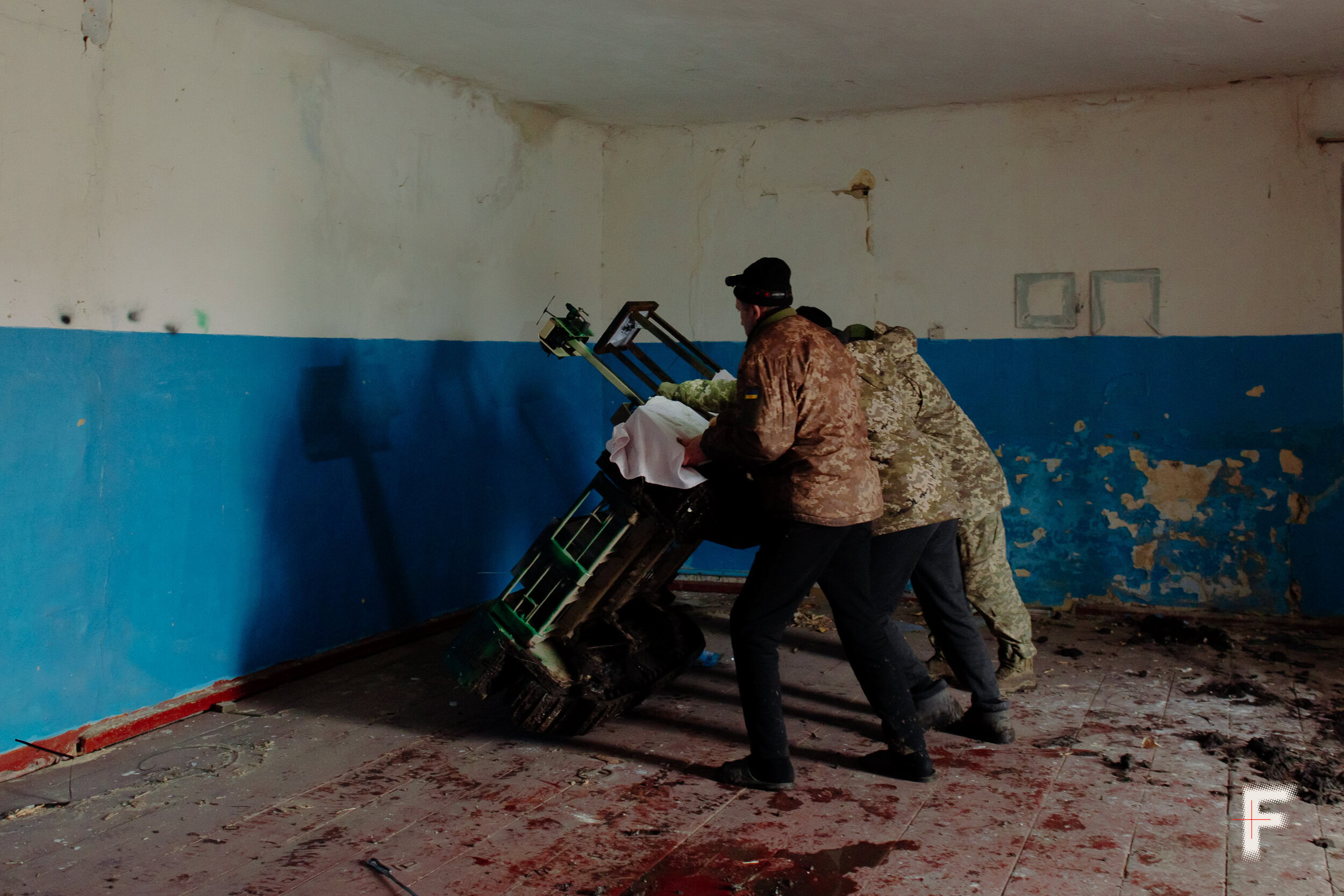 Українські військові в камуфляжі оглядають і ремонтують наземний роботизований пристрій (UGV)