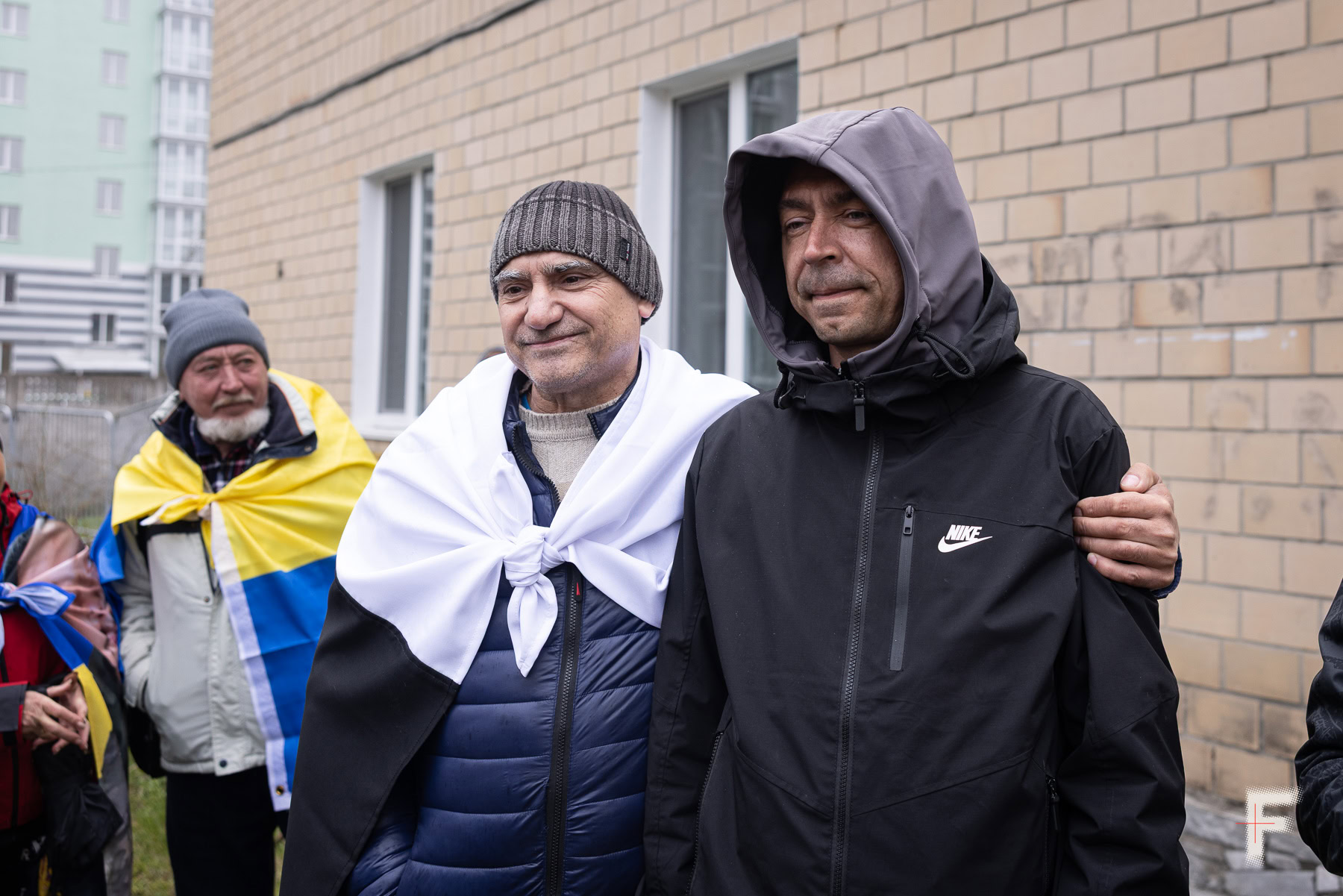 Батько обіймає сина, який повернувся з російського полону, вони підтримують родини інших полонених, Україна, 2026