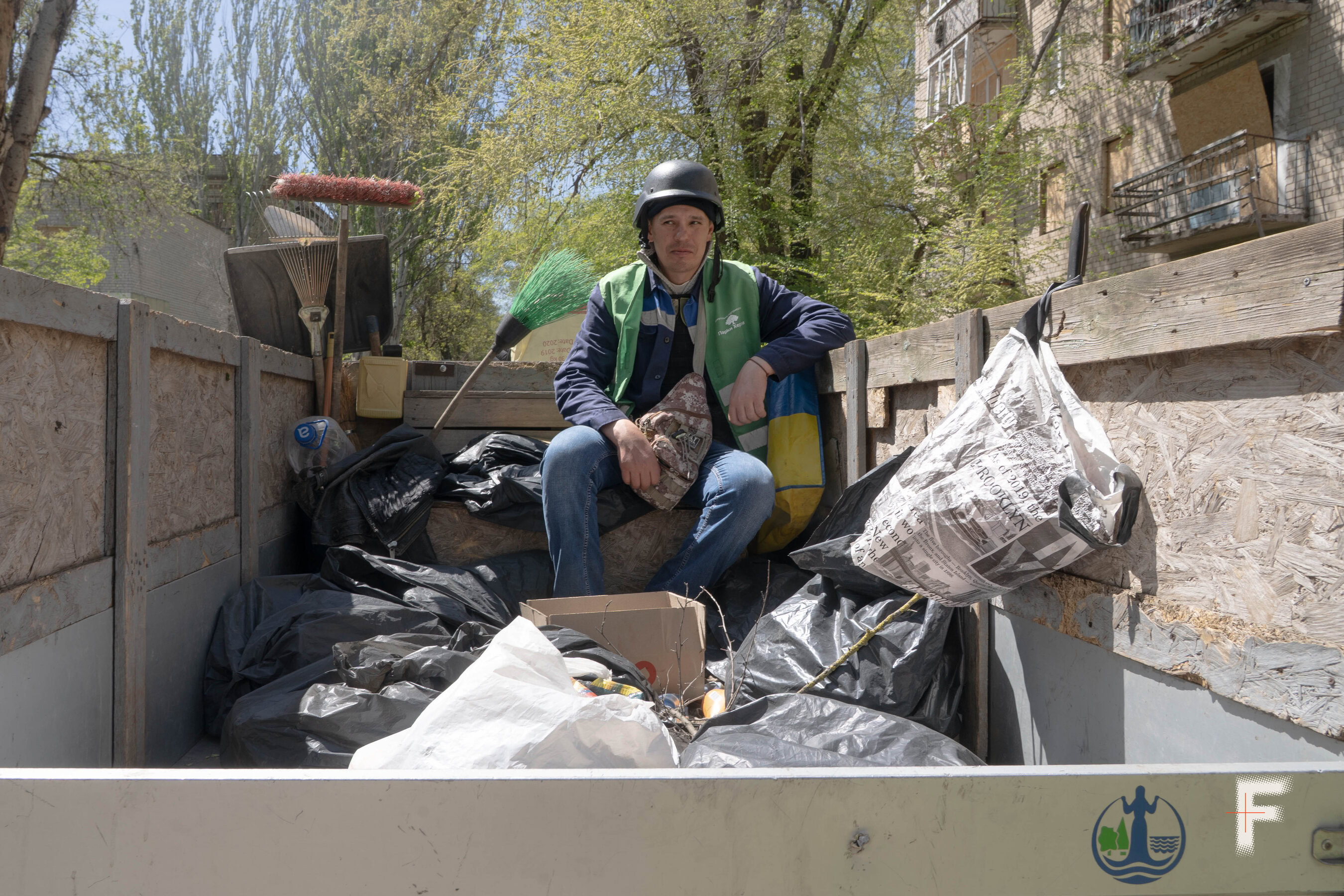 Працівник Олександр у касці сидить на сміттєвозі під час роботи в Херсоні, Україна