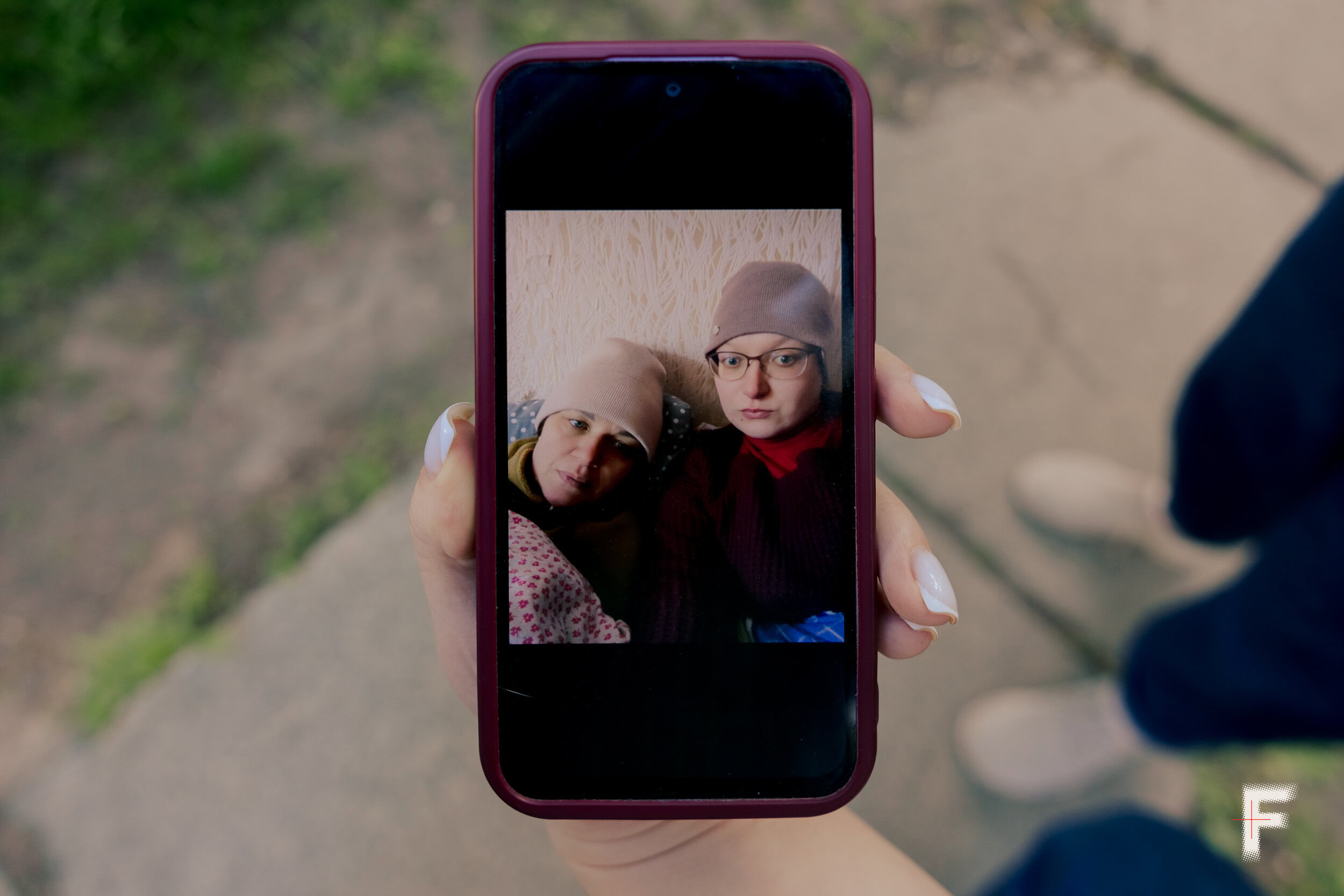На екрані телефона видно фотографію двох жінок у зимовому одязі