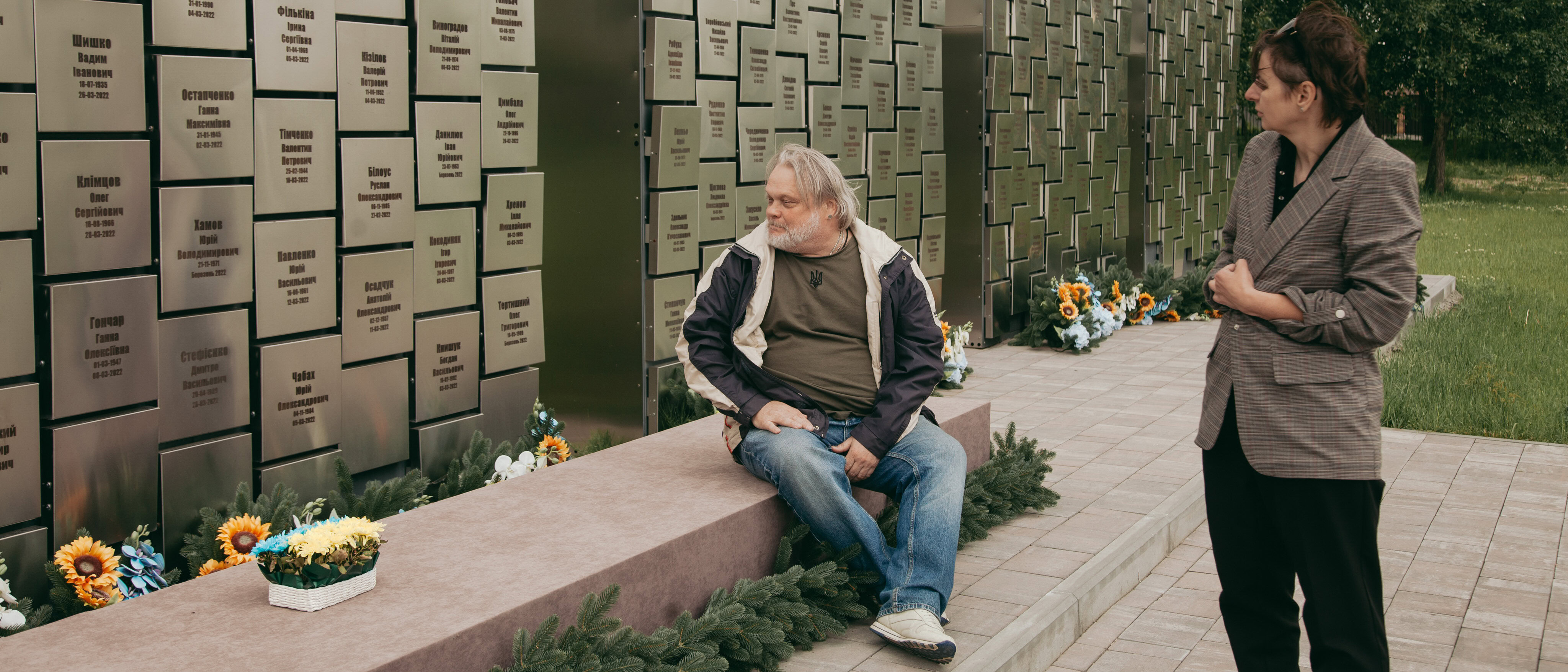 Володимир Неткач і Тетяна Корнієнко стоять біля меморіалу загиблим бучанцям «Стіна памʼяті» в Бучі.