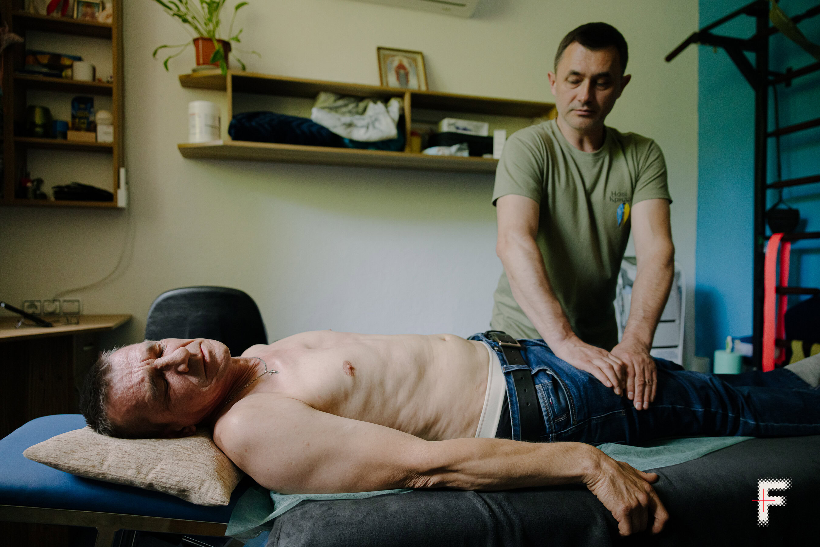 Реабілітолог тисне на грудну клітку Руслана Новальківського, щоб відновити тонус мʼязів.
