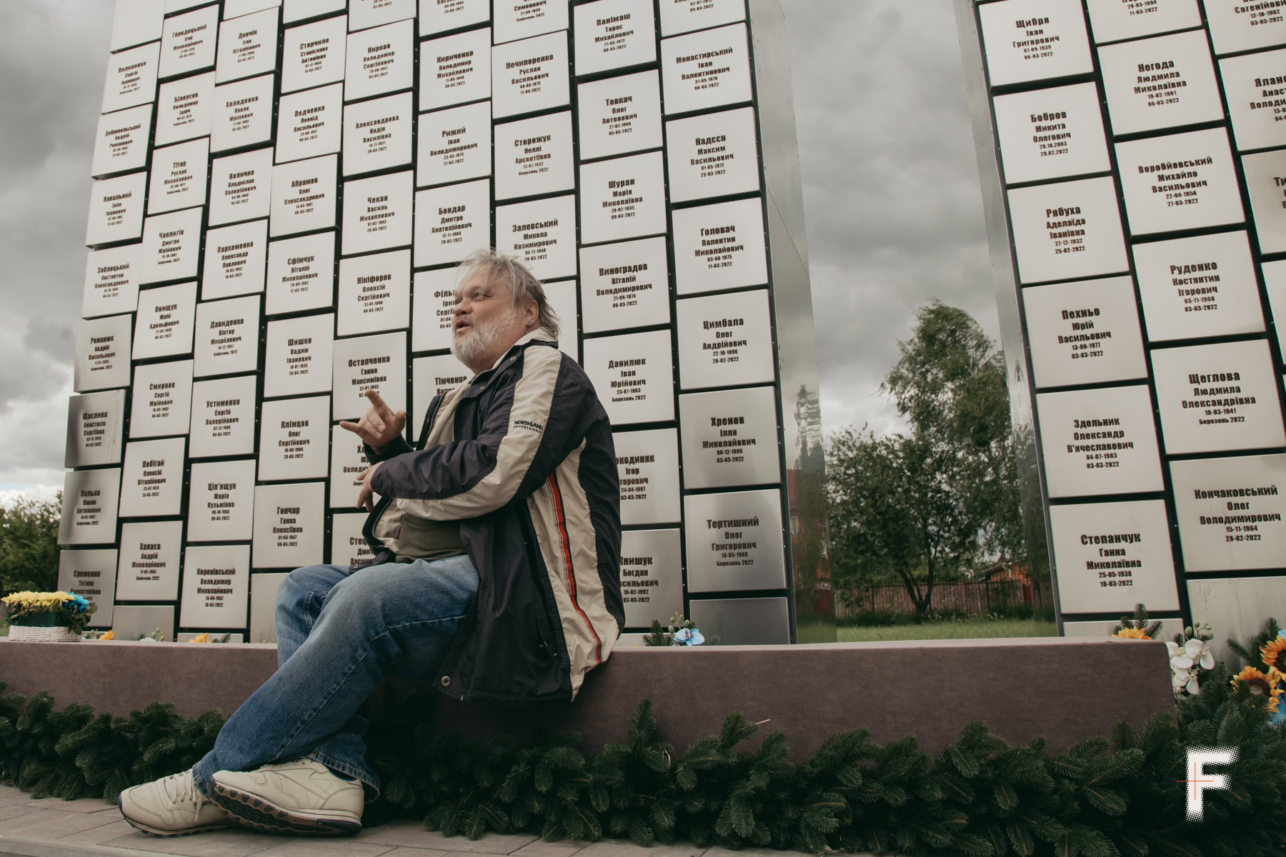 Володимир Неткач стоїть біля меморіалу «Стіна памʼяті» загиблим бучанцям.