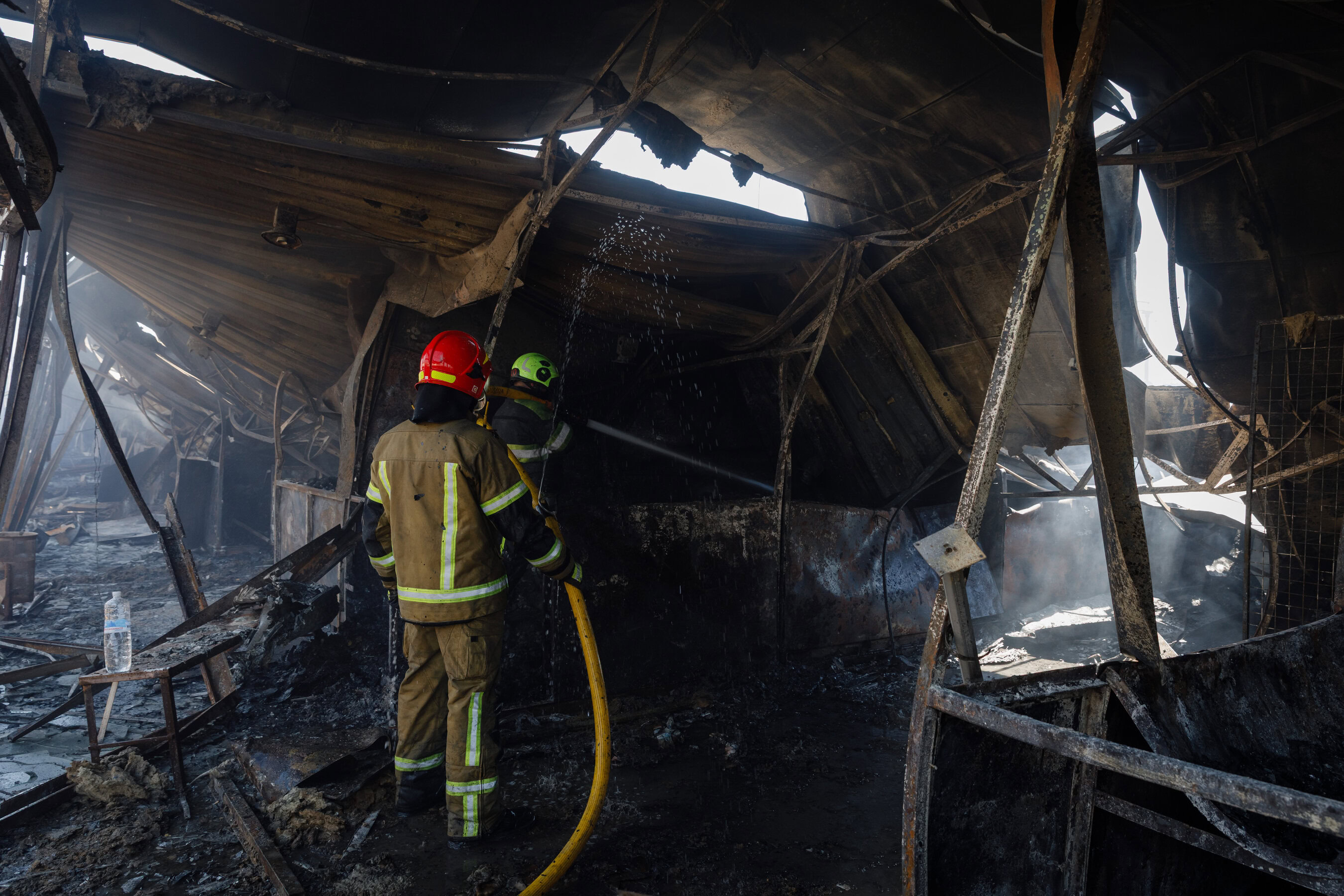 Пожежні гасять пожежу та ліквідують наслідки влучання російської ракети по книжковому ринку в Києві, 16 серпня 2026 року.